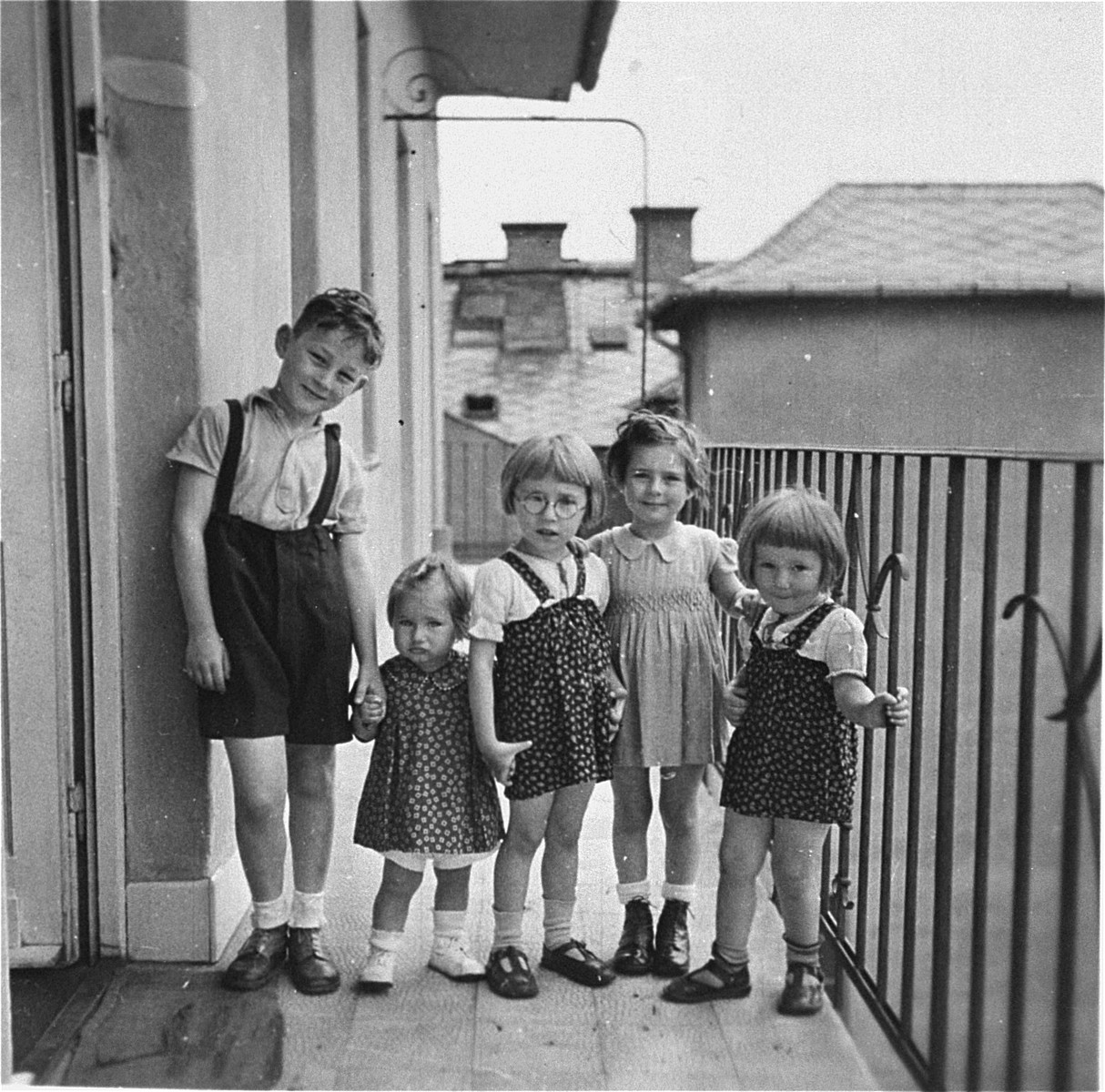 A group of children poses on the balcony of an apartment in Budapest.

Pictured are Gyorgy Pick (left), with his cousin, Clara Kornhauser (second from the left), and three non-Jewish neighbors.