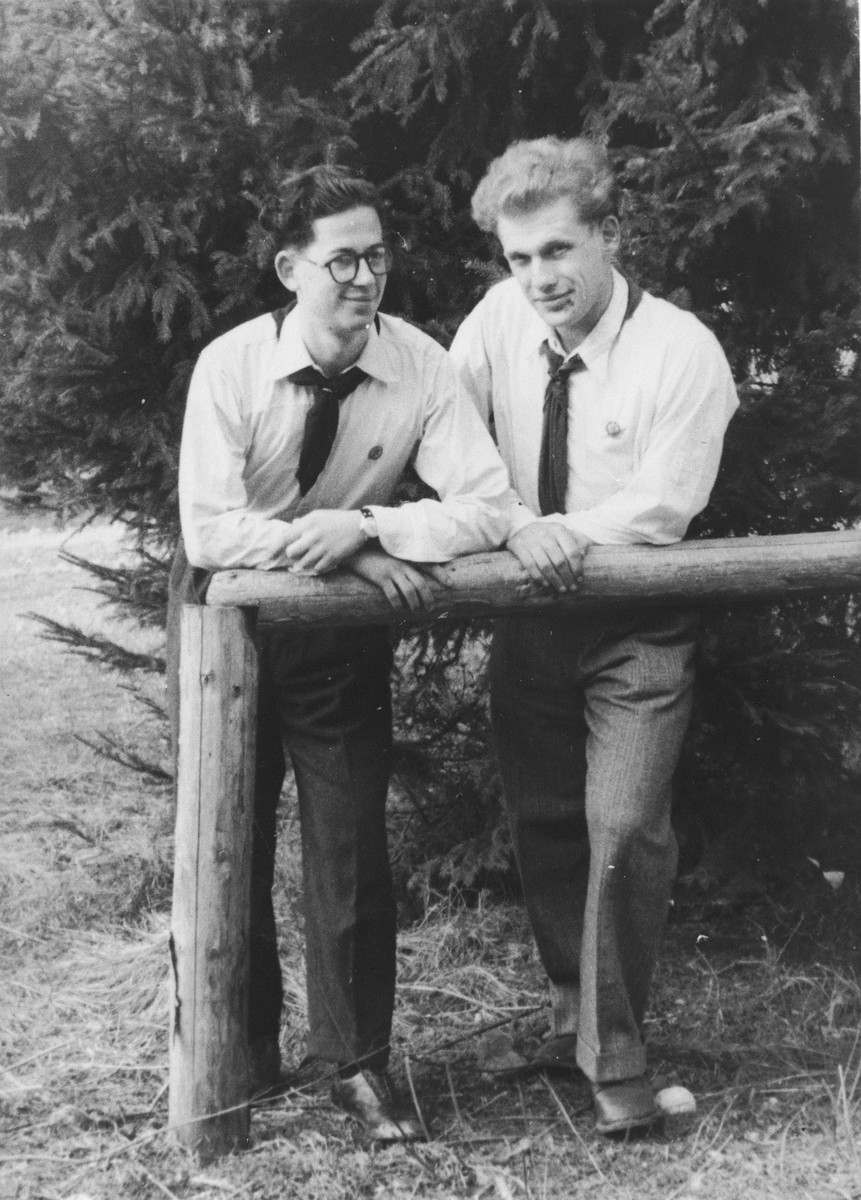 Two Jewish DP youth who numbered among the Exodus 1947 passengers, stand behind a wooden railing in the Poppendorf displaced persons camp.

Pictured are Benno Ginsburg (right) and Jacques Rabinovich (left).