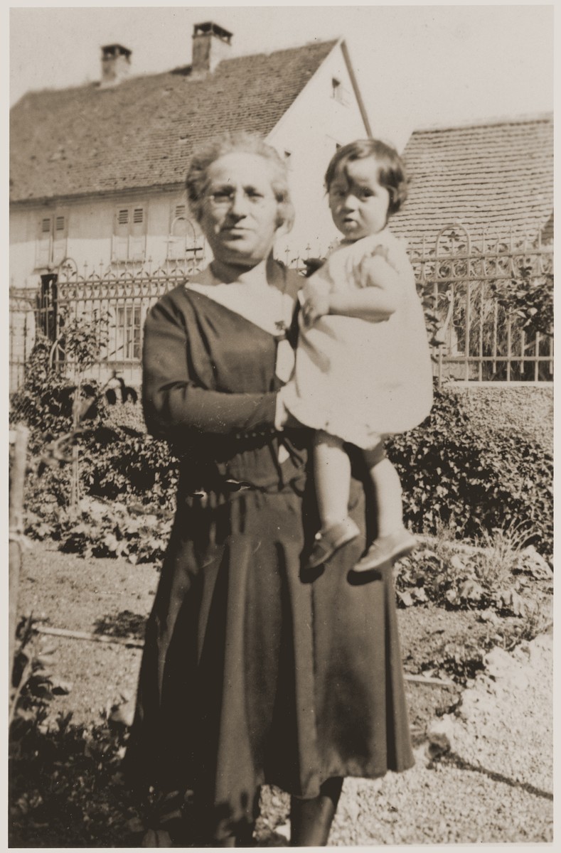 Suse Grunbaum is held by her great-aunt,  Adele Kahn in front of the home of her grandmother, Frieda Kahn.