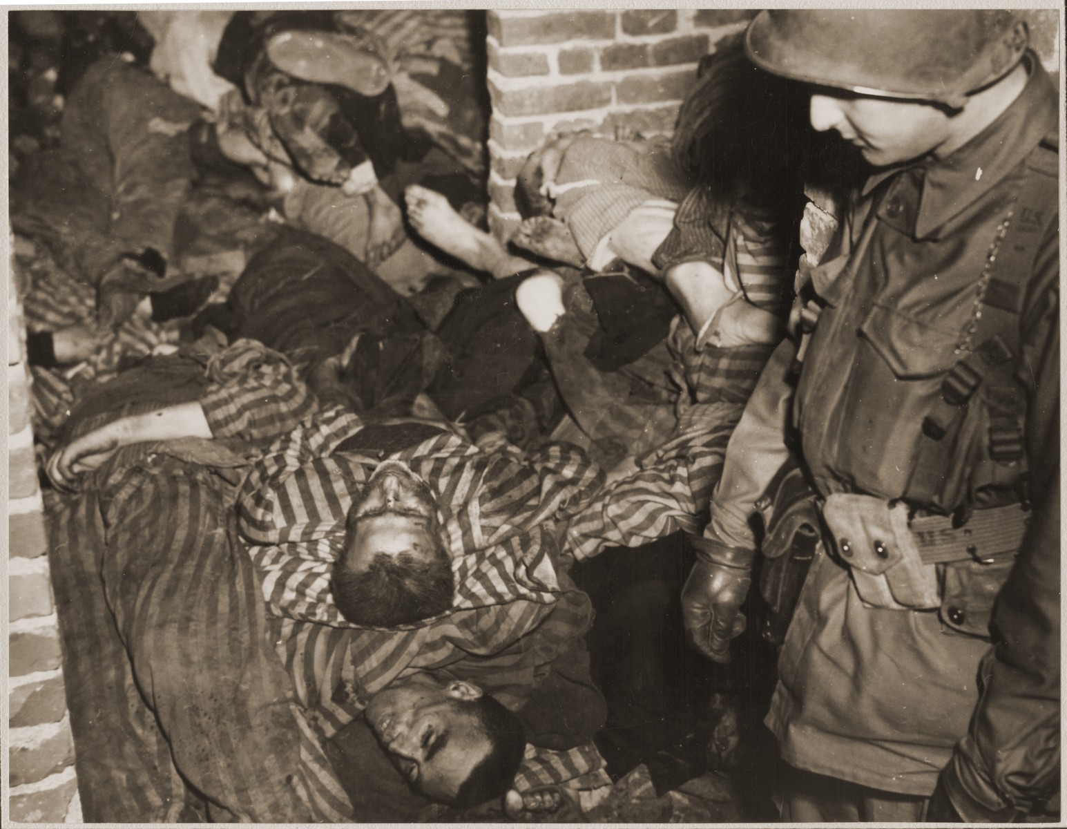 An American soldier views the bodies of prisoners that are piled in a brick structure in the newly liberated Woebbelin concentration camp.