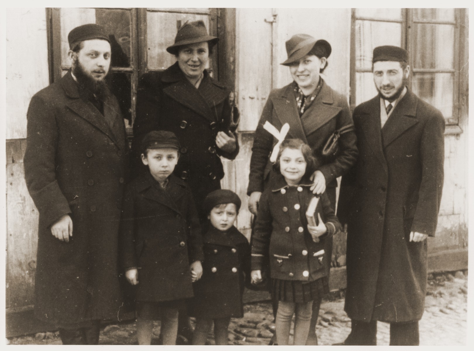 Portrait of the Tenenbaum in front of a house in Warsaw.

Pictured standing (from left to right) are: Pinchas Tenenbaum and his wife, Fajgl (Warszawska)Tenenbaum; Nechama and Srulik Tenenbaum.  In front are Pinchas' three children.