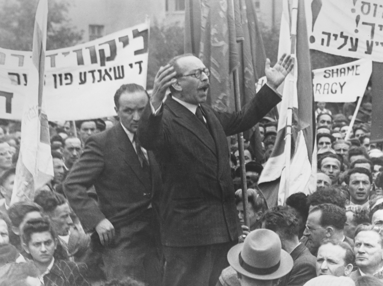 Marc Jarblum addresses a crowd of Jewish DPs at a demonstration in the Bergen-Belsen displaced persons camp that called for free immigration to Palestine and protested the return of the Exodus 1947 passengers to Germany. 

Also pictured are Josef Rosensaft (standing behind Jarblum) and Norbert Wollheim (in profile on the right, near the front).