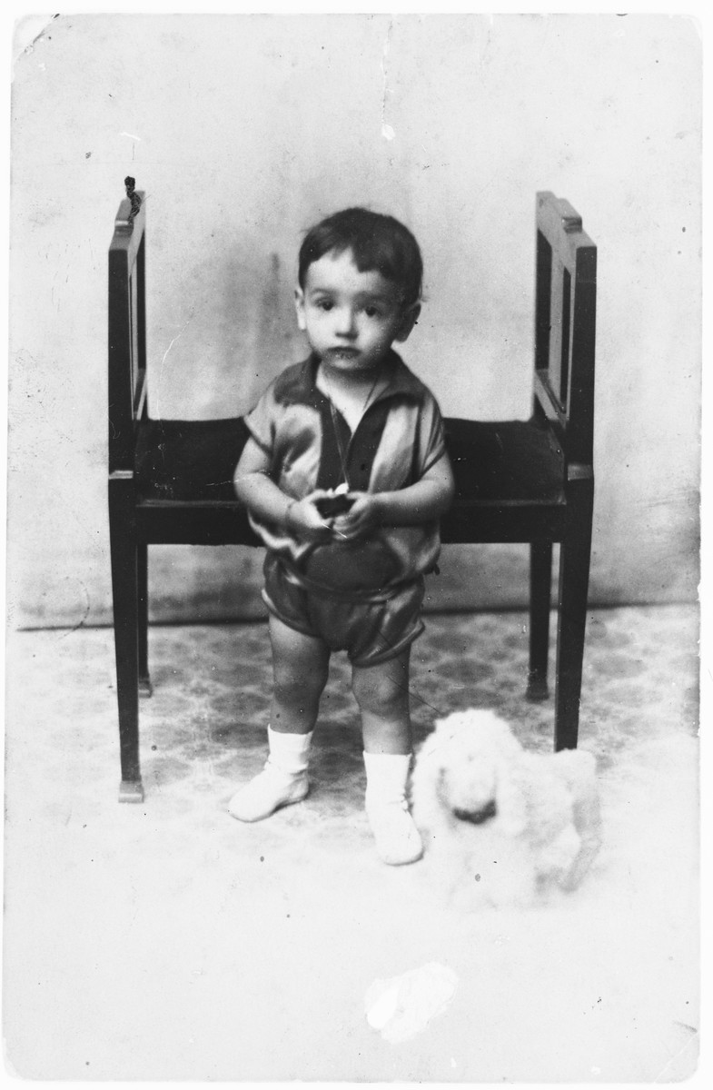 Studio portrait of Isaac Nehama with a toy dog at his side.