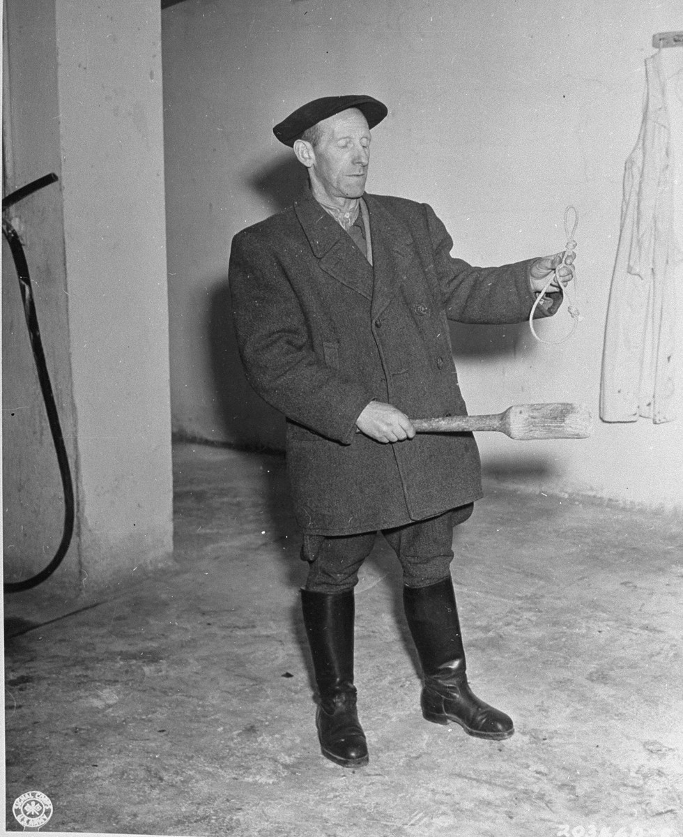 The new caretaker of Buchenwald concentration camp displays a noose and club used by the SS to murder prisoners.  He was appointed by Third Army officers in the Military government.