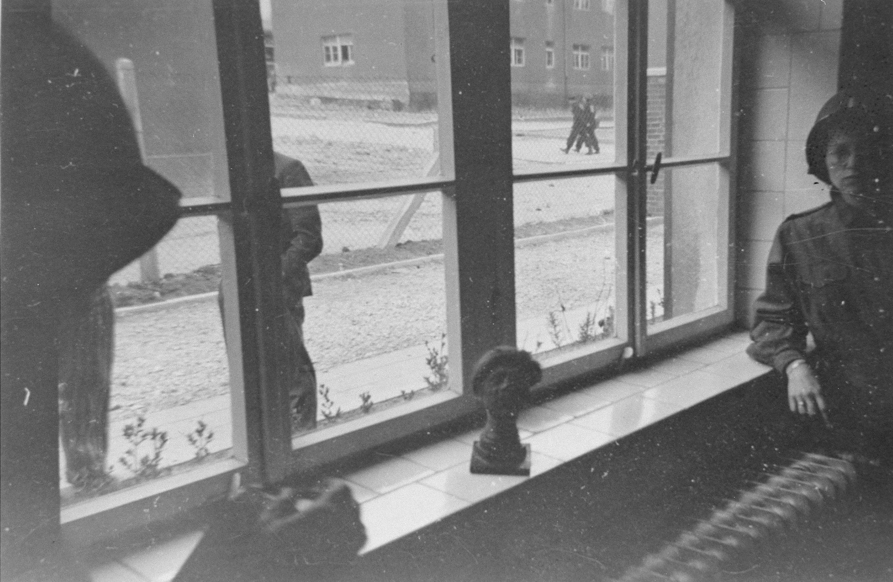 An American soldier stands next to a shrunken head perched on a windowsill in a building in Buchenwald.