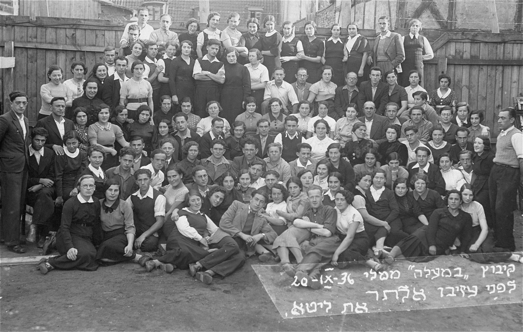 Group portrait of the kibbutz hachshara, Bemaaleh, taken on the occasion of the departure of one of its members.  

Pictured at the far left is Eliezer Kaplan, the donor's father.