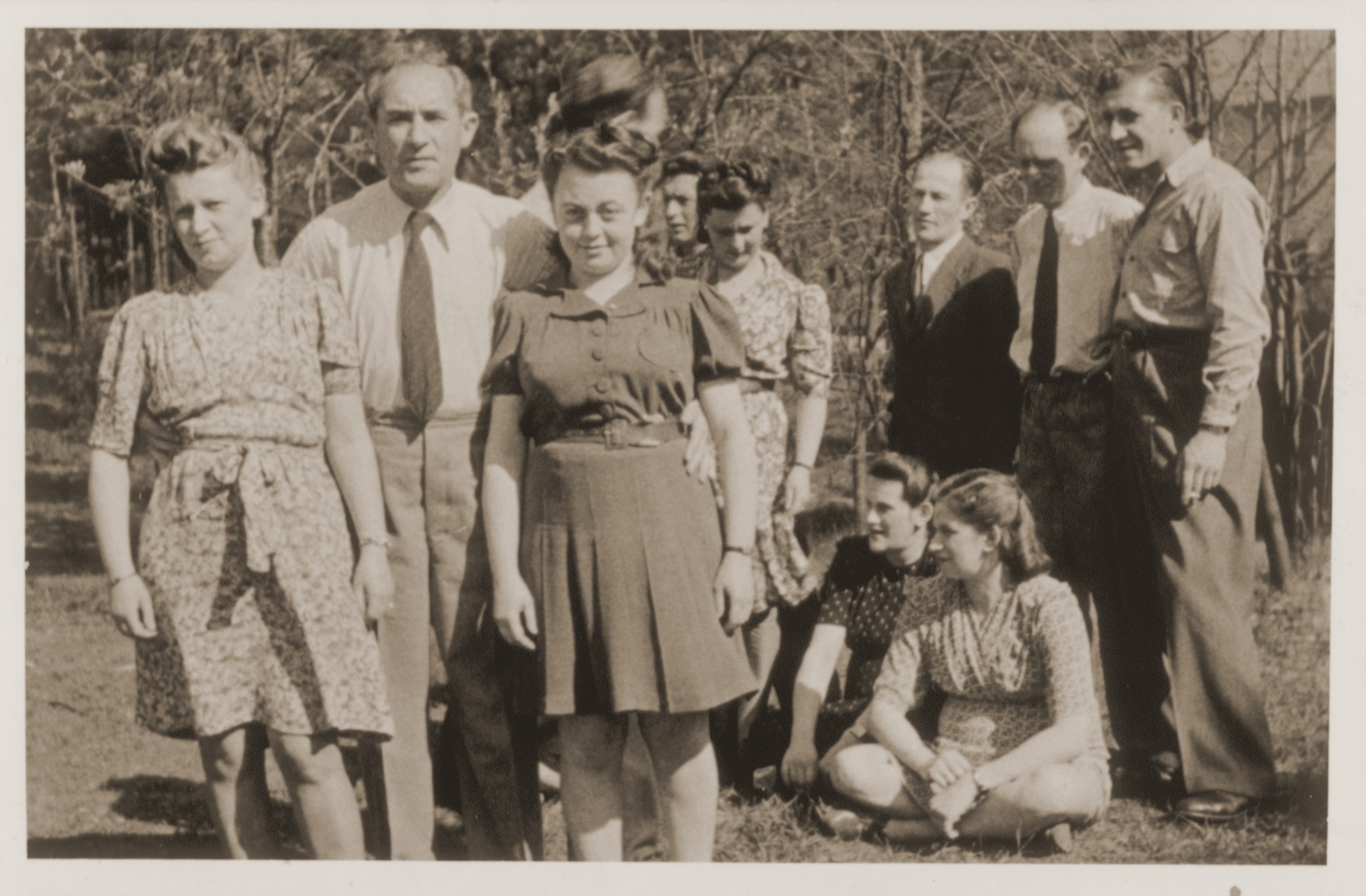 A group of Jewish DPs at the Schlachtensee displaced persons camp.  

Standing from left to right are: Guta Tencer, Moses Tencer, Chana Tencer, Pola Zyngier, Moshe Frymerman, Rachmiel Zyngier, and unidentified.  Seated from left to right are: Renia (Kilman) Frymerman and Eva (Kilman) Zyngier.

Verso is signed "Hania."