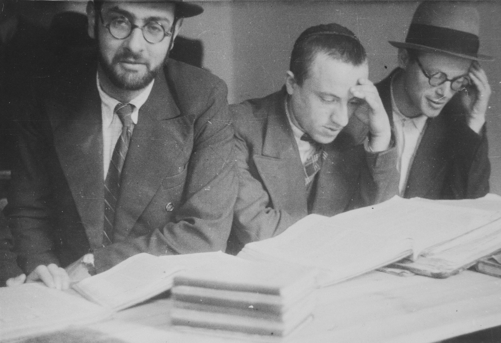 Students at the Mir Yeshiva in Kobe study around a table.

Elchanan Yosef Hertzman is on the right and Boruch Yaakov Alter is in the middle.