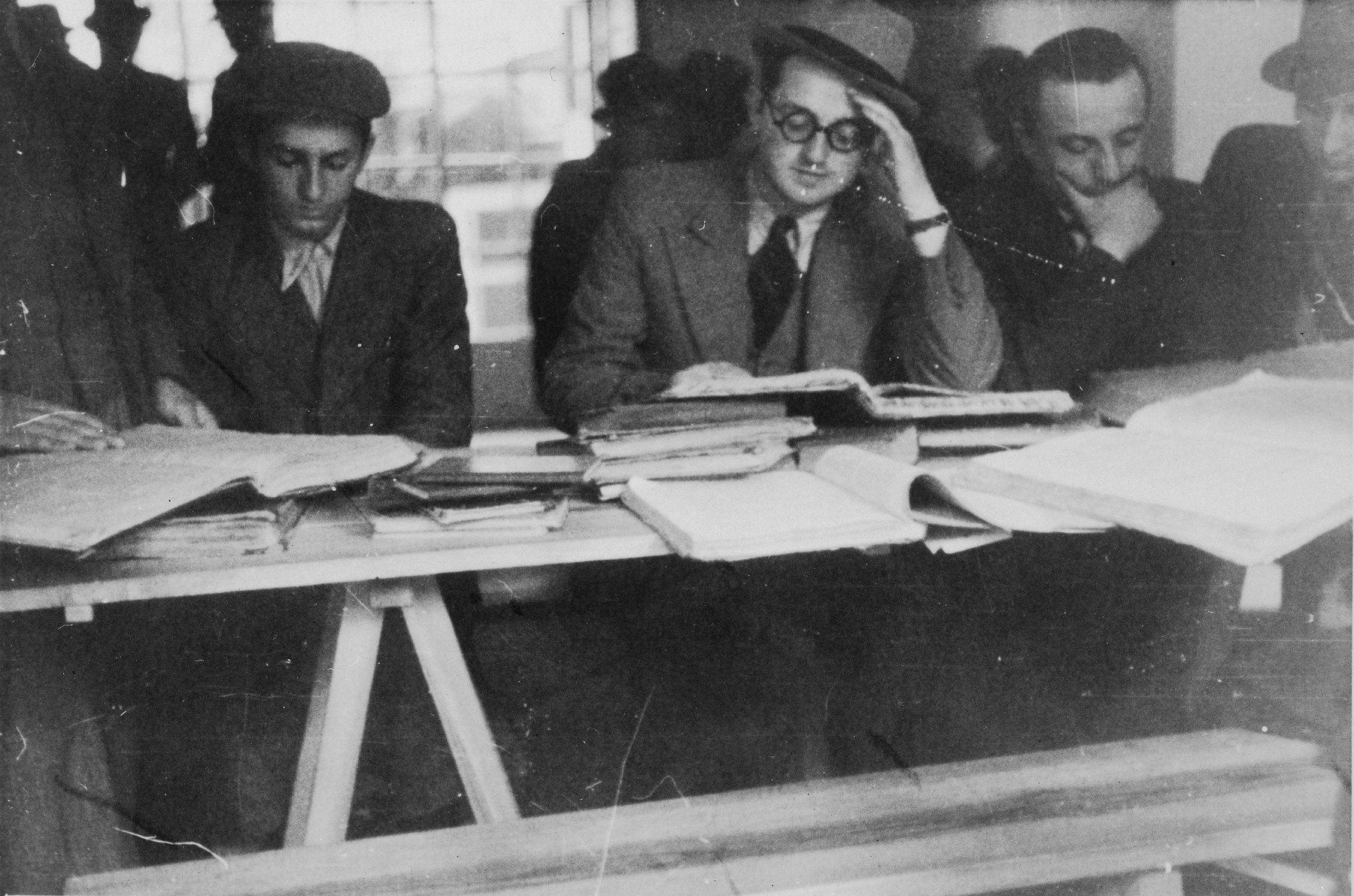 Students at the Mir Yeshiva in Kobe study around a table.

Rabbi Avraham Blumenkrantz is seated in the center and on the far right is Boruch Yaakov Alter.