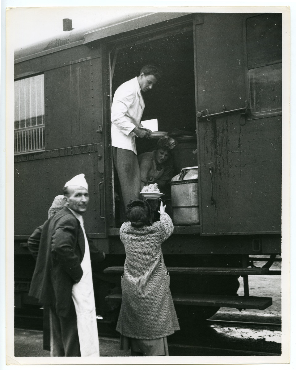 Displaced persons unload food supplies from a train.