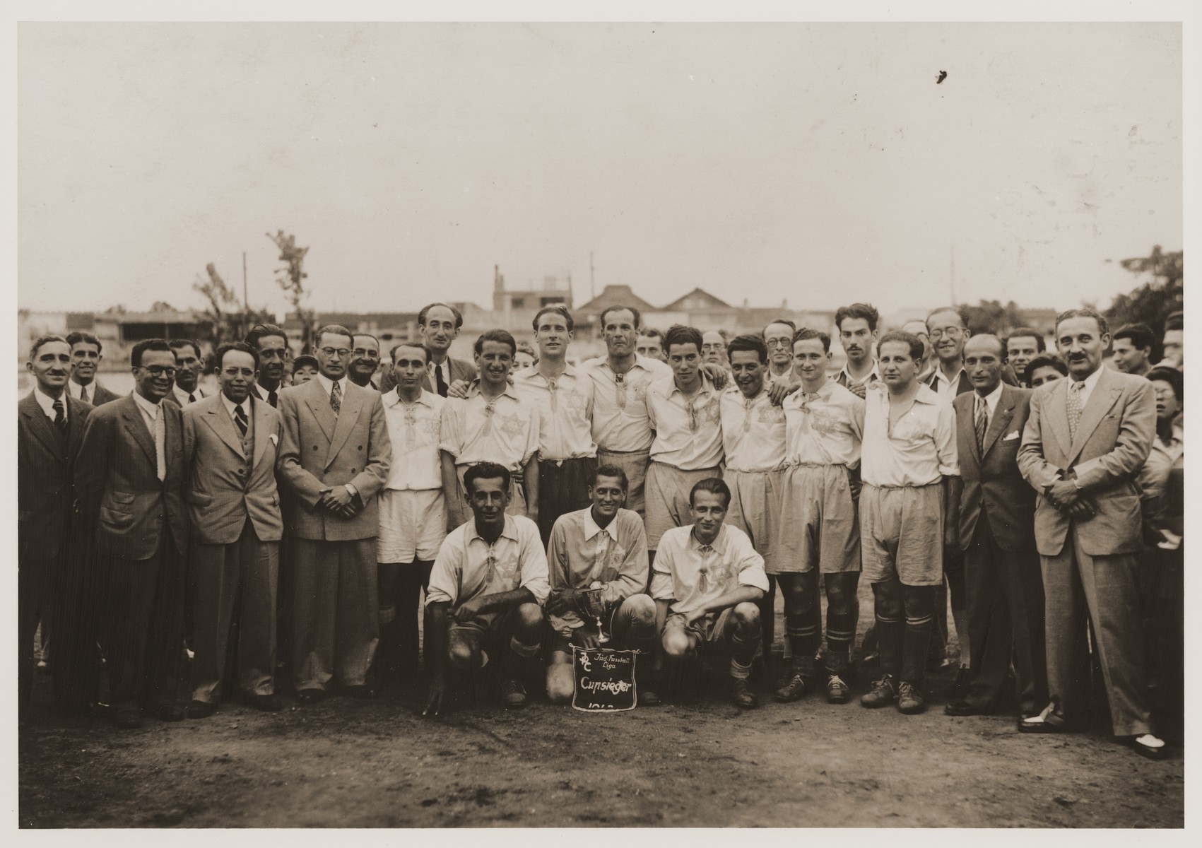 Group portrait of members of the S.J.C soccer team which won the Jewish Refugee Committee of Shanghai championship in 1943.  

Eric Goldstaub is kneeling, first on the right.