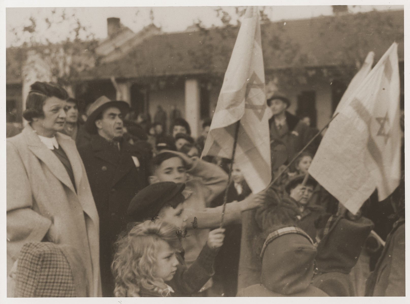 Harry Fiedler and other students wave Zionist flags during a celebration at the Kadoorie School.   

Standing on the far left is school principal, Lucie Hartwich.