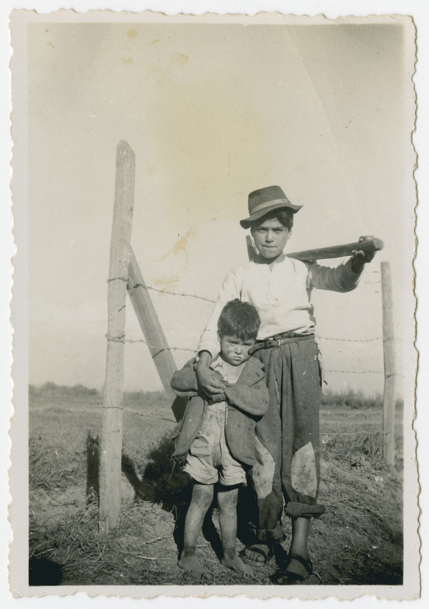 Photograph from an album entitled, "Hacshara Kidma Chile,"  documenting life on a postwar Shomer Hatzair Zionist agricultural collective in Chile.

Two young Chileans pose by a barbed-wire fence.  The inscription on back (in Spanish) reads, "Manolo and Enrique."