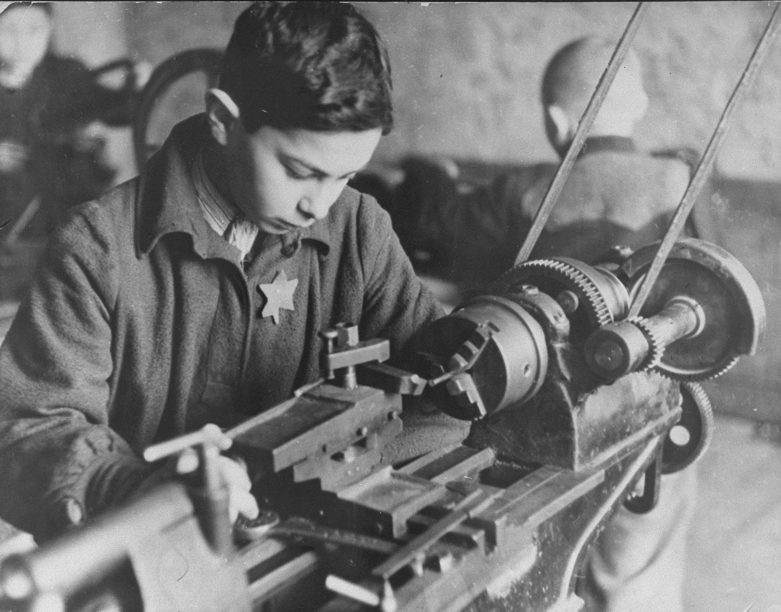 A boy works at a machine in a Kovno ghetto workshop.

Pictured is Yakob Vizgordiski.