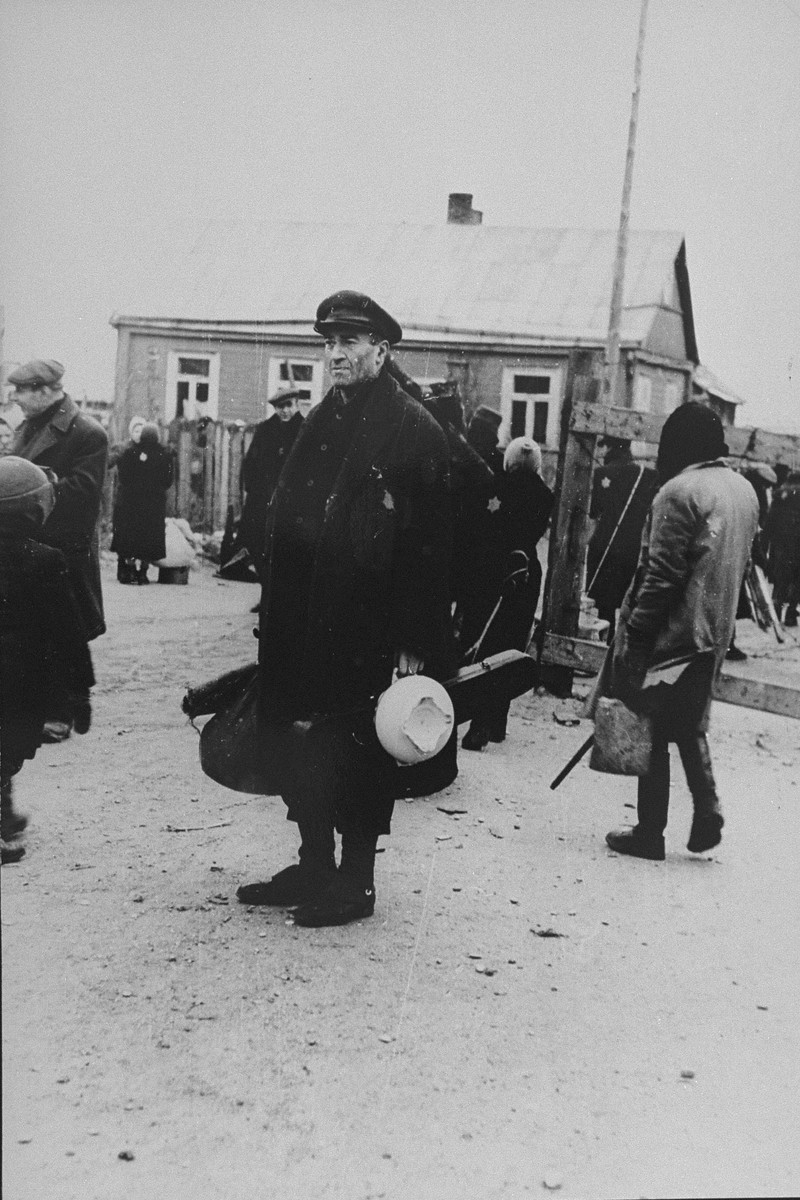 Alexander (Shmaya) Stupel, a well-known German-Jewish violinist and a member of the Kovno ghetto orchestra, stands outside with his instrument case.
