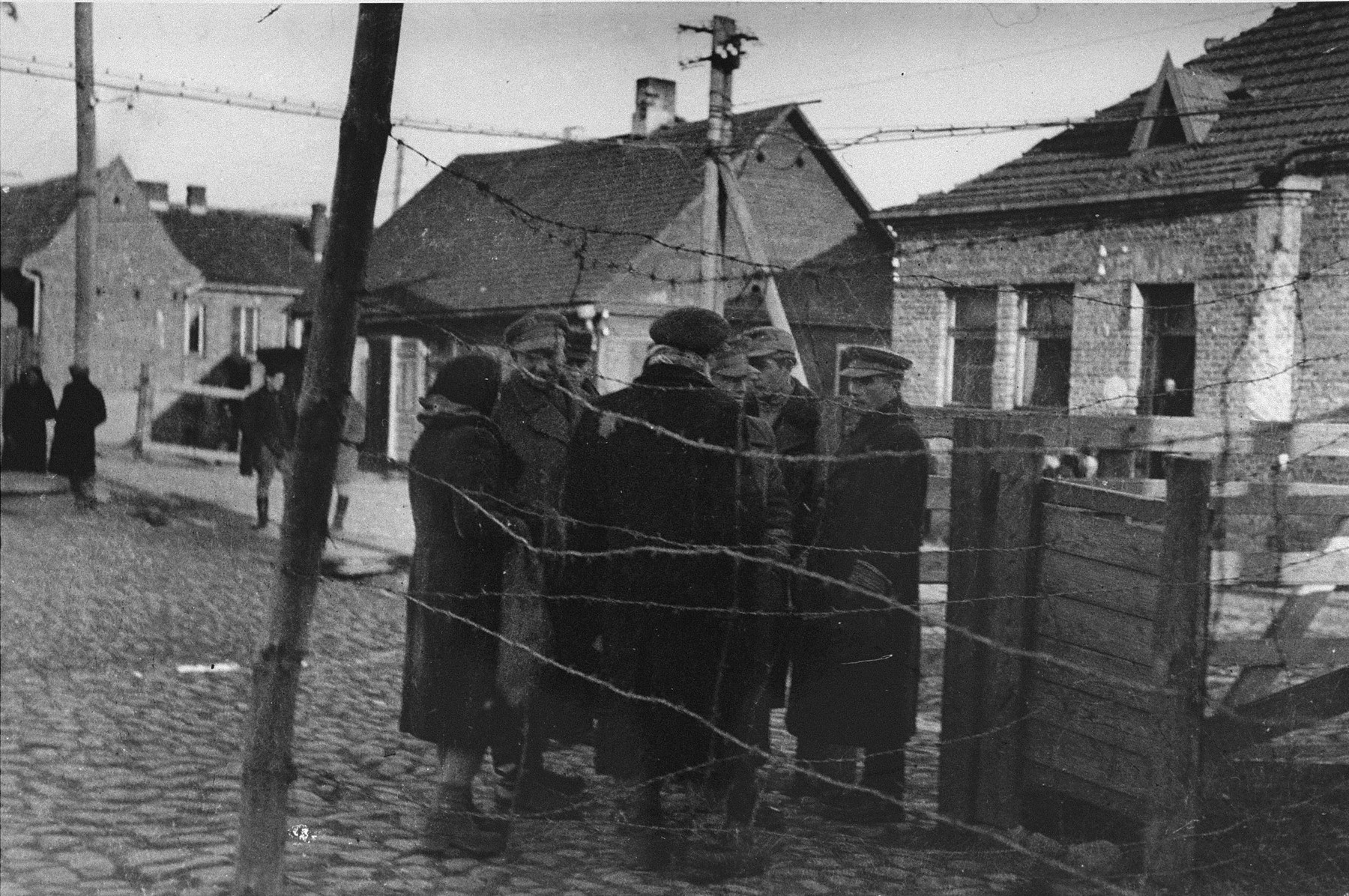 Jacob (Yankel) Verbovski (far right), a representative of the Altestenrat labor office, talks with a group of Jews near the Varniu Street entrance to the Kovno ghetto.

Verbovski was known as the ghetto's "count man".  He was in charge of counting people coming and going into the ghetto.  In that capacity he helped members of the resistance to escape from the ghetto, and he helped smuggle weapons and other illegal goods into the ghetto.  Verbovski survived the war and immigrated to the United States.