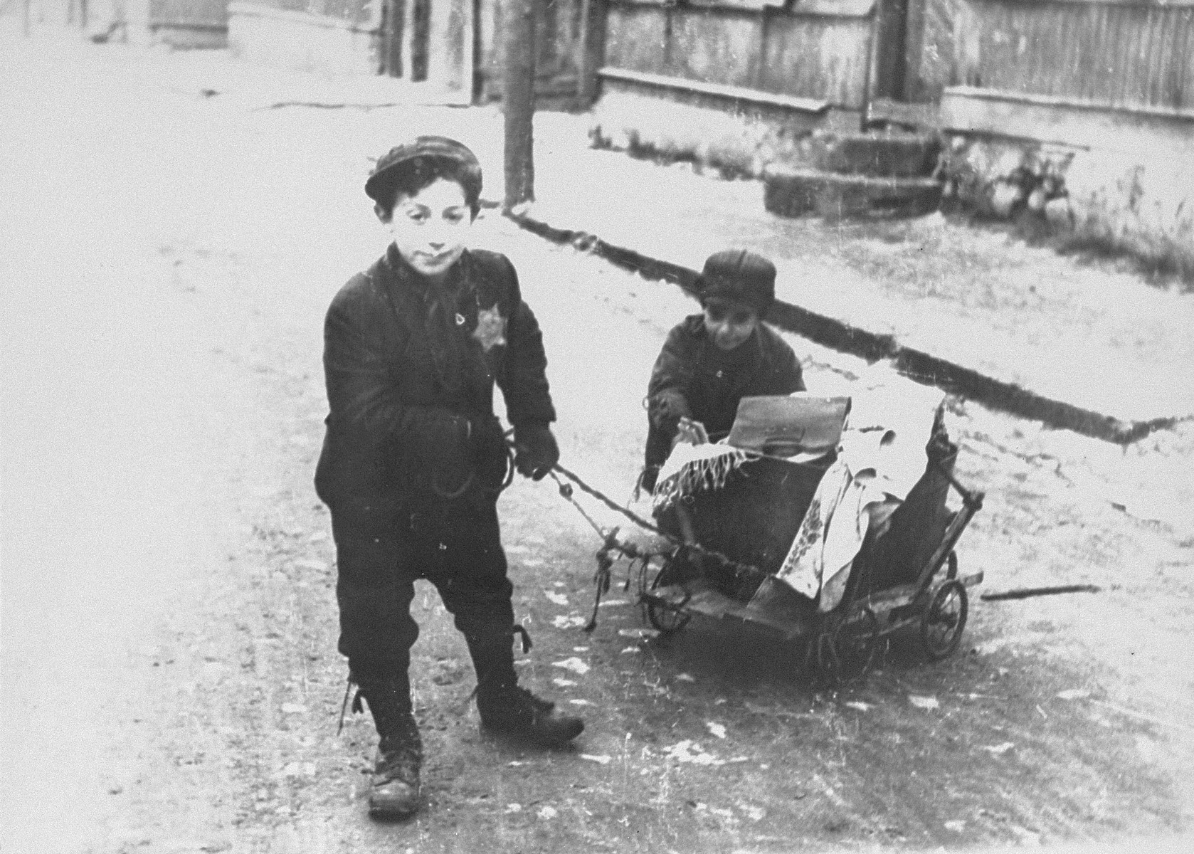Two young boys pull and push a wagon in the Kovno ghetto. 

According to Solly Ganor: "Two orphans whose parents were murdered in the beginning of the war. There were many children like them in the ghetto. They lived with a sick grandmother in half a room sharing with other two families. He was the provider of the family, trading, stealing and begging. I would see him at the corner "market" place, trying to sell old shoes, torn garments and old books. He, his little brother and his grandmother were murdered at the "Children's Action". "