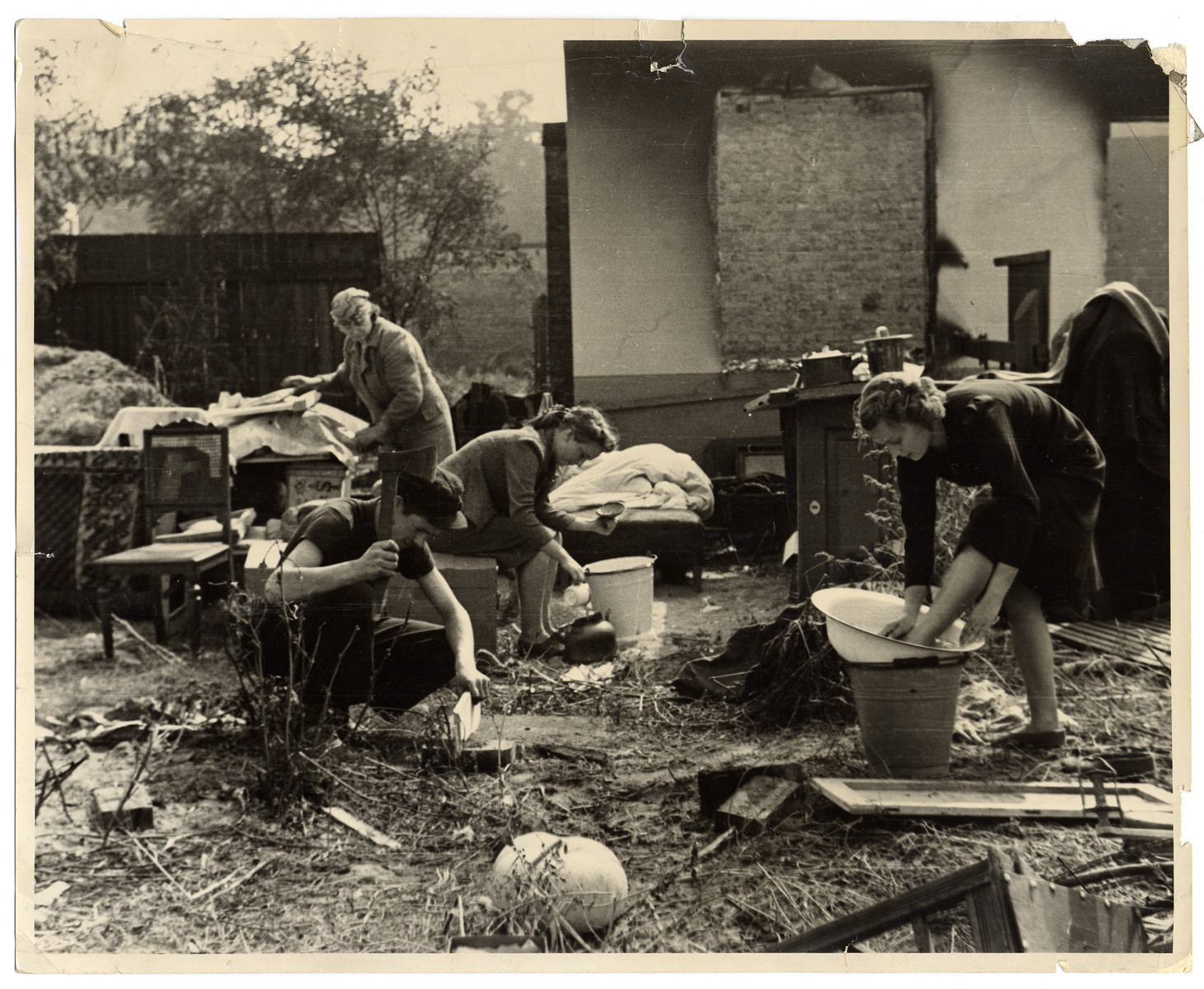 A Polish family performs their daily chores amidst the remnants of their household furnishings that they have reassembled outside the charred ruins of their home in Warsaw.