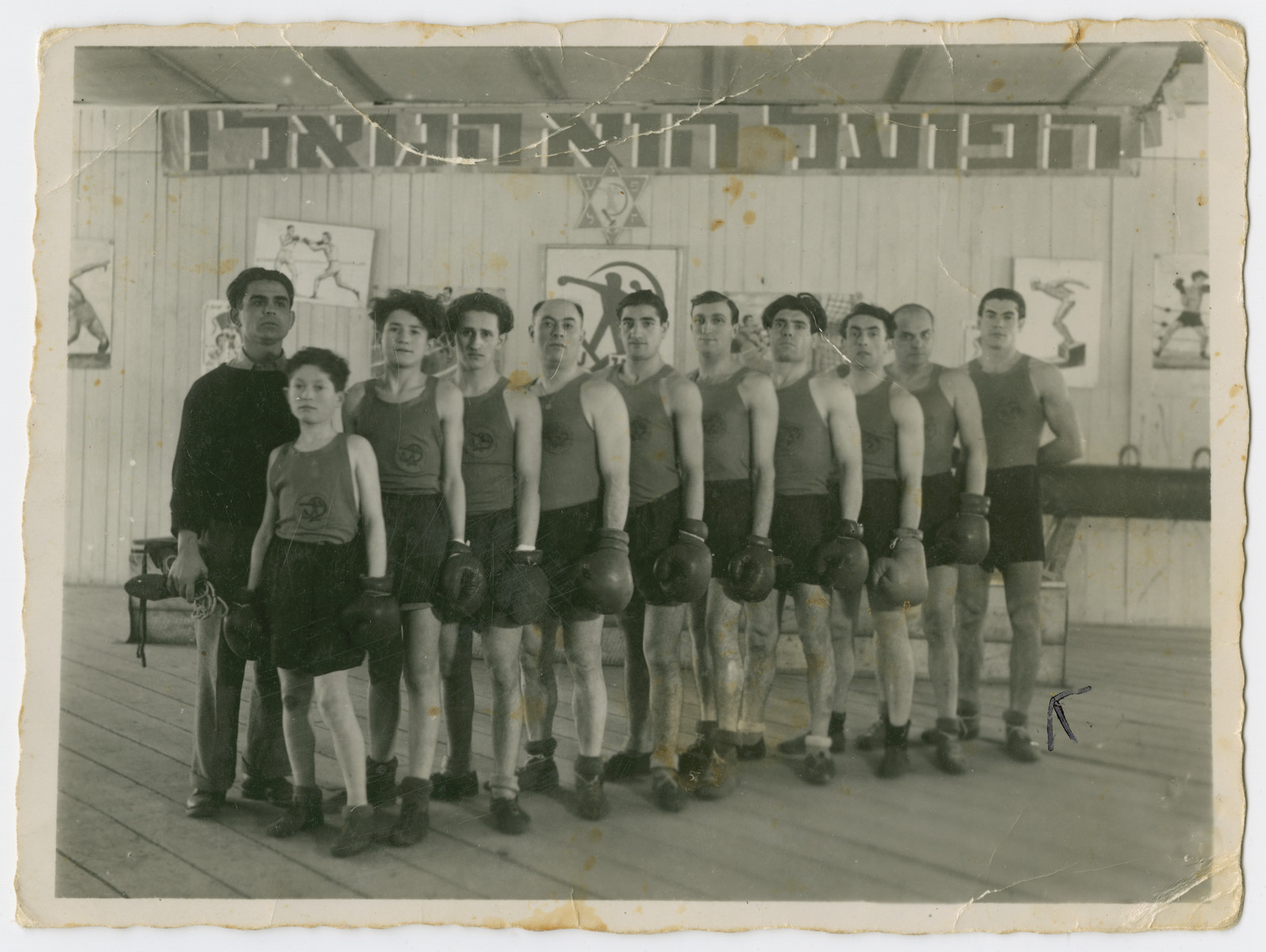 Group portrait of the members of the boxing club in Feldafing.

Richard Gutnner is at the end of the row.  The sign in Hebrew reads "HaPoel Hu HaGoel" [The worker is the redeemer.]