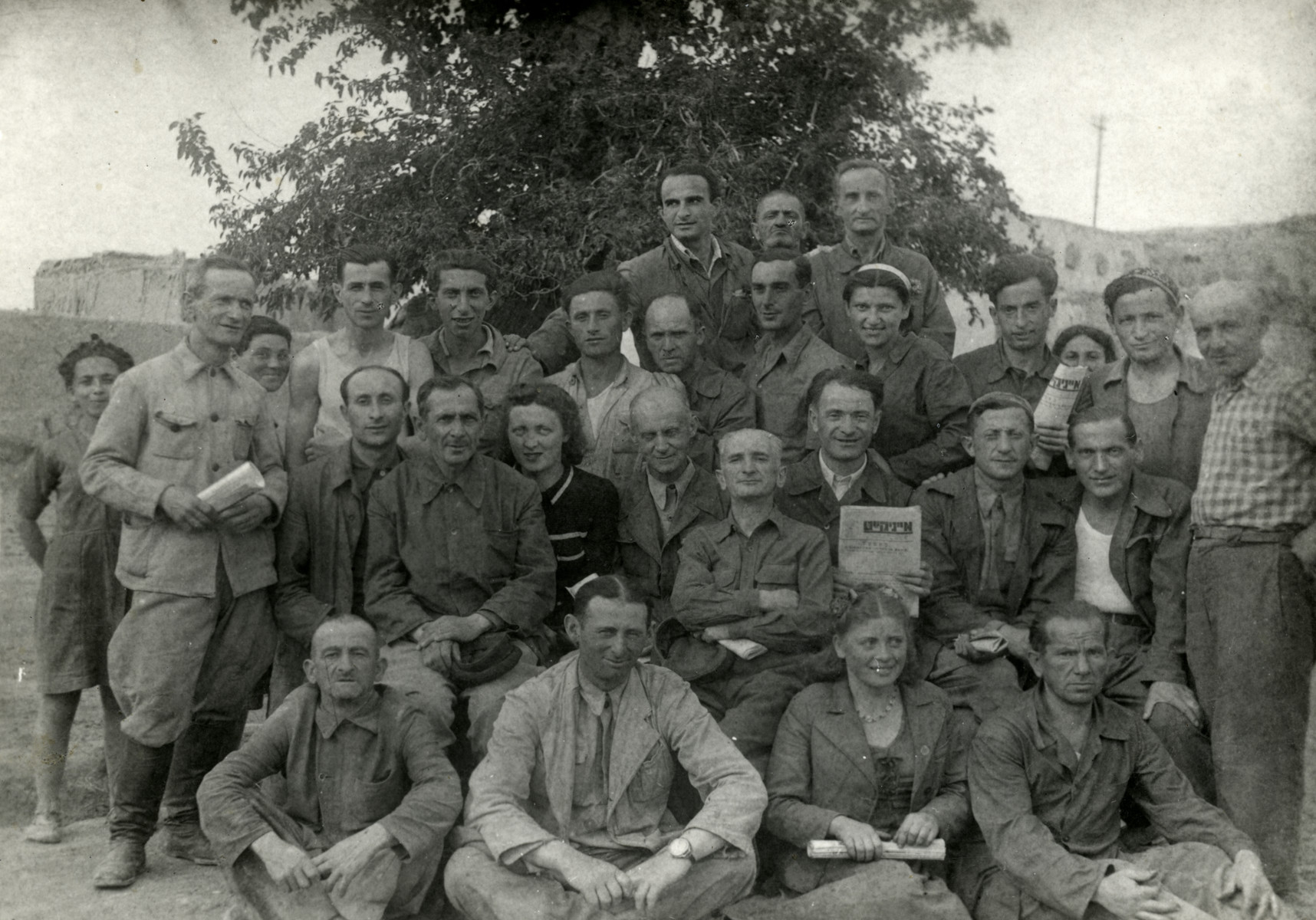 Group photograph iof Jewish refugees in Bukhara, some holding Yiddish newspapers.

Jonas Markowicz and Abraham Levine are sitting on the right of the second row.