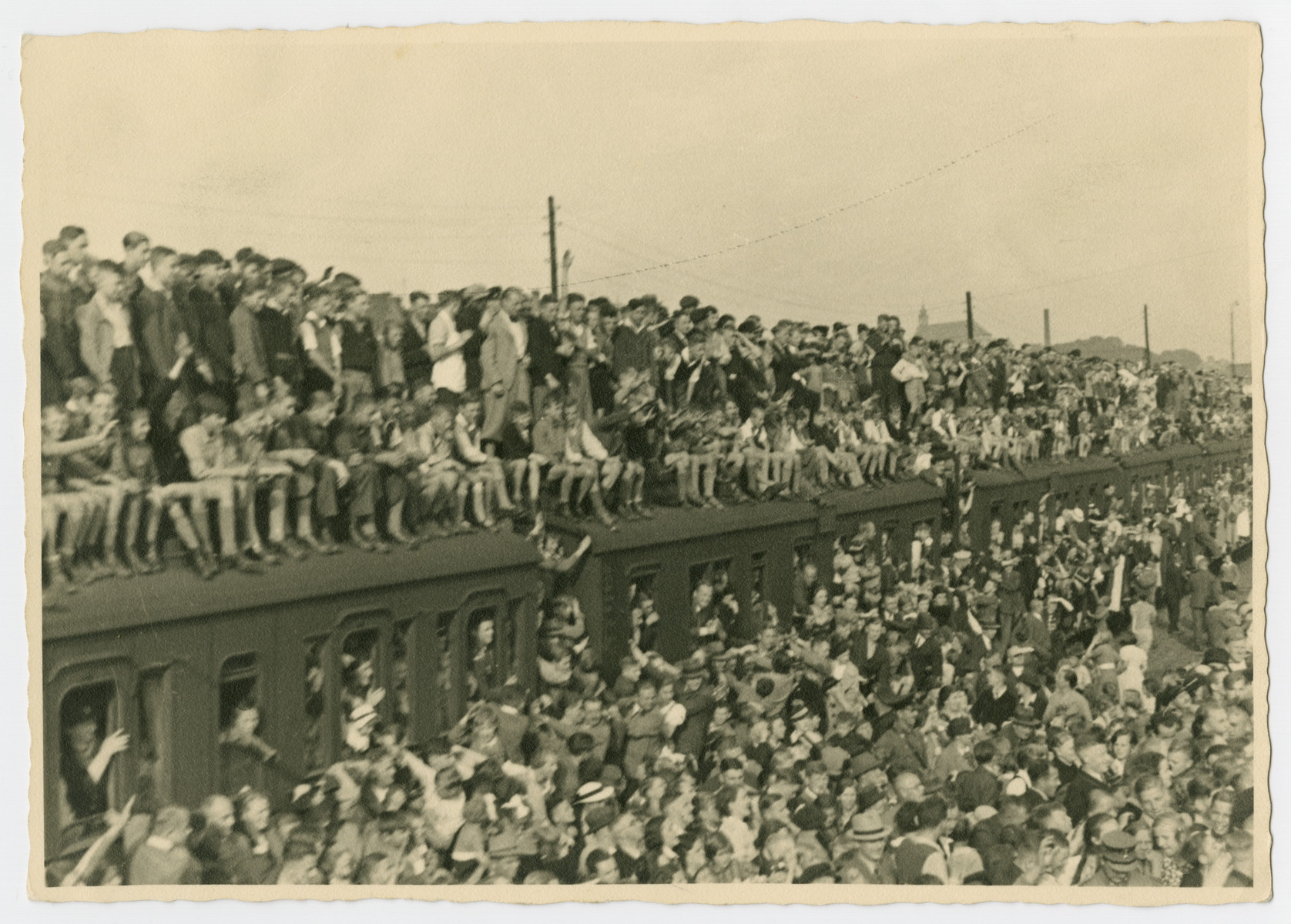 Crowds of people gather in front of and on top of a train to participate in a May Day Nazi party parade.