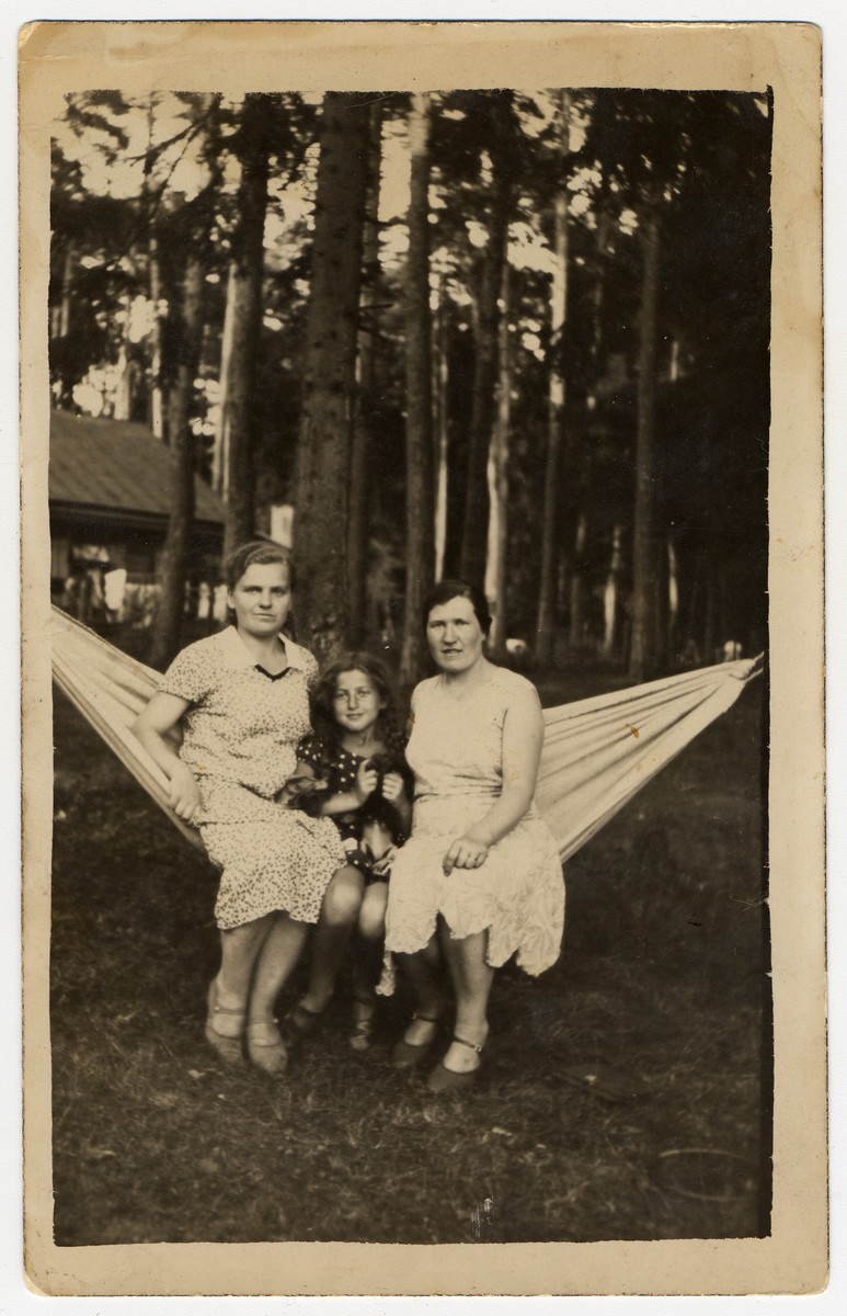 A Lithuanian Jewish woman and her daughter sit together on a hammock with their Lithuanian housekeeper.

Pictured from left to right are Franute Grunskaite, Sara Ginaite and Rebecca Giniene.  Franute Grunskaite was later recognized by Yad Vashem as Righteous Among the Nations for saving Sara's cousin, Tania Viroviciene.