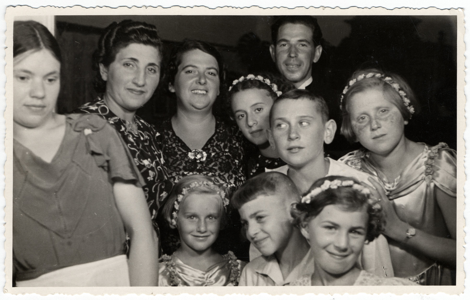Group portrait of Latvian Jews at a wedding celebration.

Lia and Bella Levenstein (far left) pose in matching dresses among relatives and friends, during the wedding of David Levenstein and Hanna Thalberg in Ventspils, Latvia.  Frieda Lewenstein, Libin and Bella's mother (2nd from right), is also pictured. Neither Frieda nor her daughters survived the Holocaust.