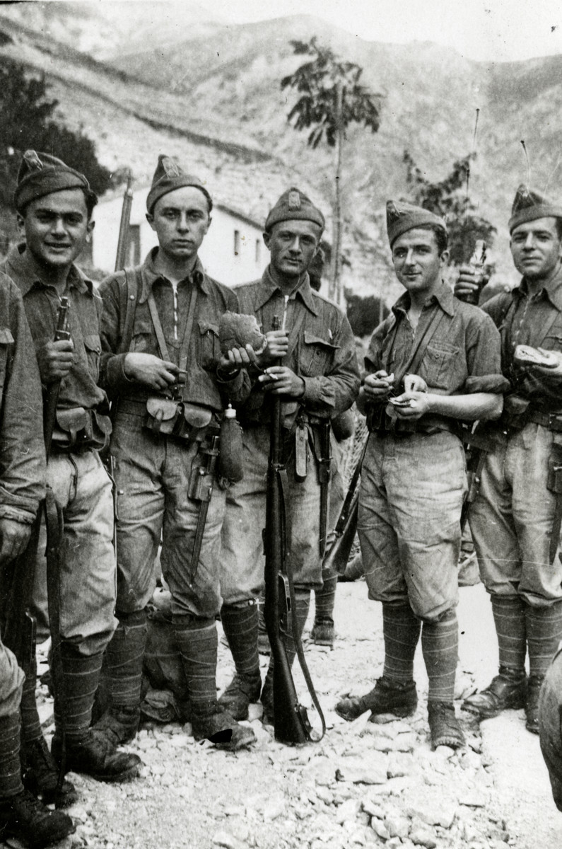 Five Italian soldiers pose with their weapons in a base near a mountain.

Pictured on the far left is Ugo Nizza.