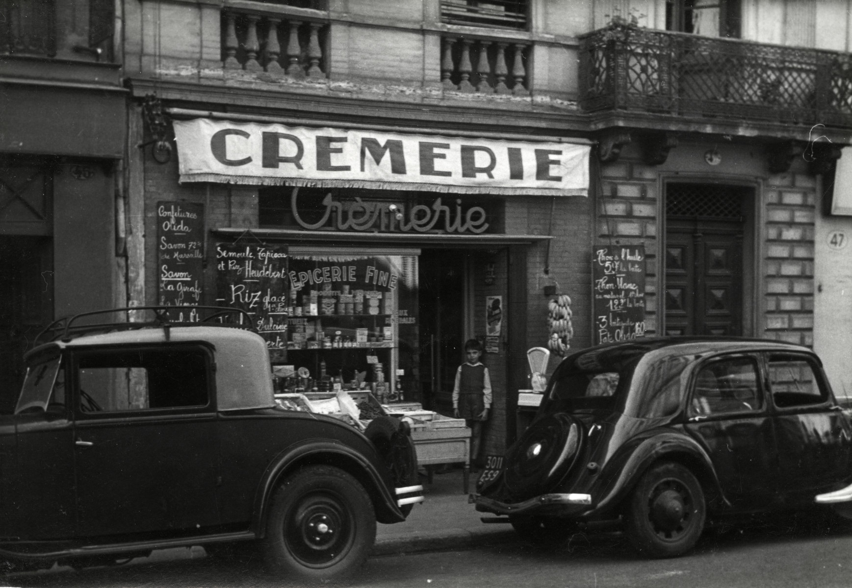 View of two automobiles parked outside the Cheraki's grocery store in Toulouse, France.