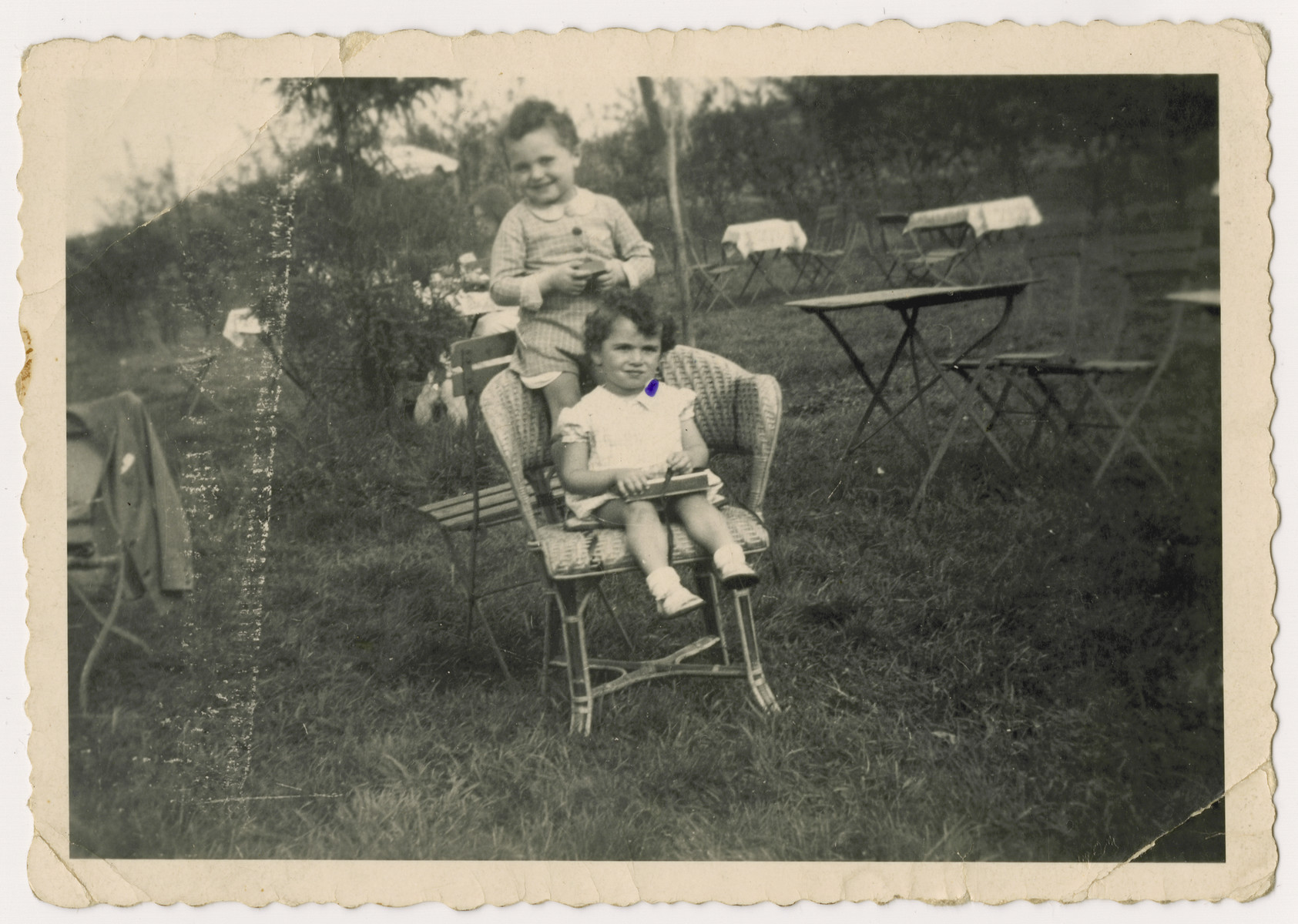 Two Jewish children placed in a children's home before  the invasion of Belgium, seen posing on a chair at a corner cafe dring their mother's weekend visit.  

Pictured are Nestor and Jacques Hochglaube.