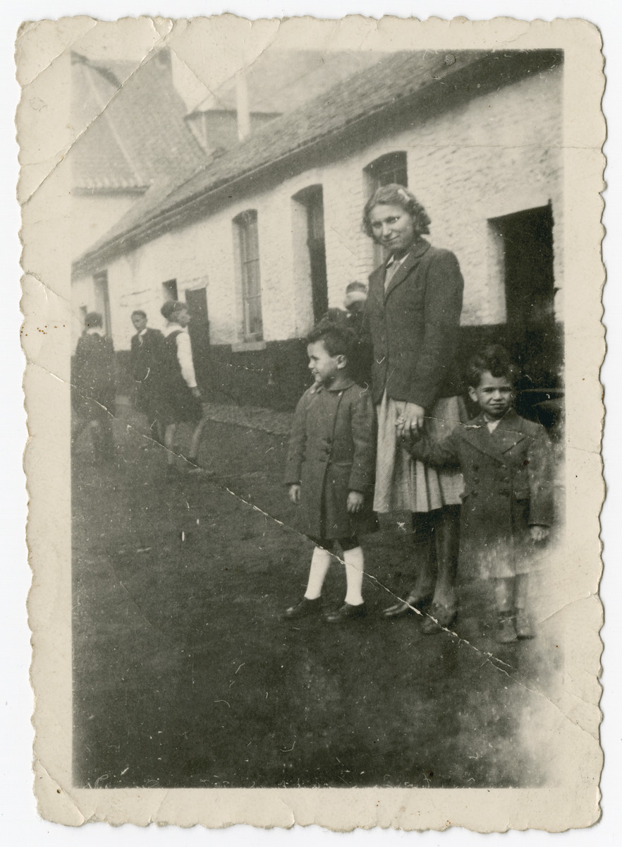 Two Jewish brothers stand on either side of the German maid who is hiding them on her farm in the Belgian countryside.  

Pictured is Nestor Hochglaube (right) and his brother Jacques.