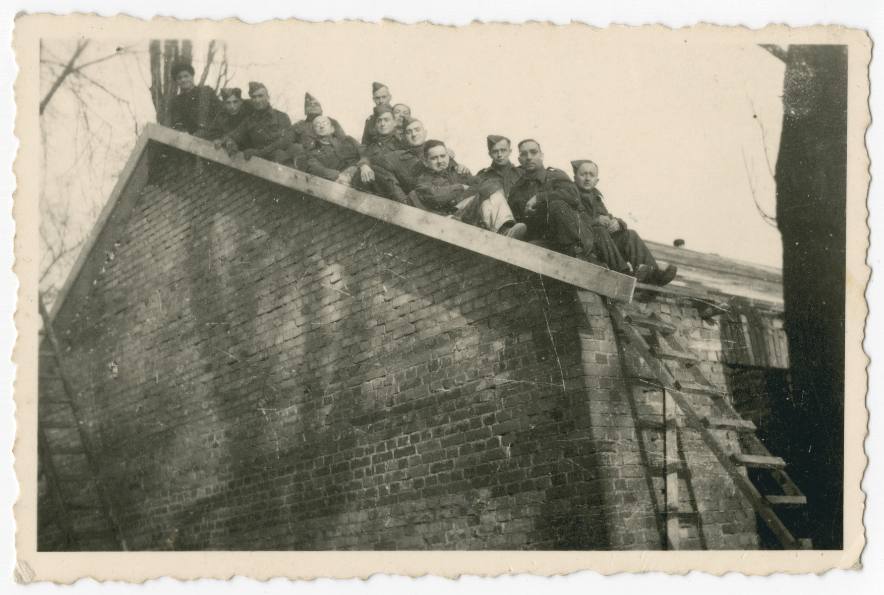British POWs in Stalag IV A, Elsterhorst pose on the roof of a brick barrack.

Among those pictured is Erich de-Beer, a Germany Jew who immigrated illegally to Palesline and joined the British army.