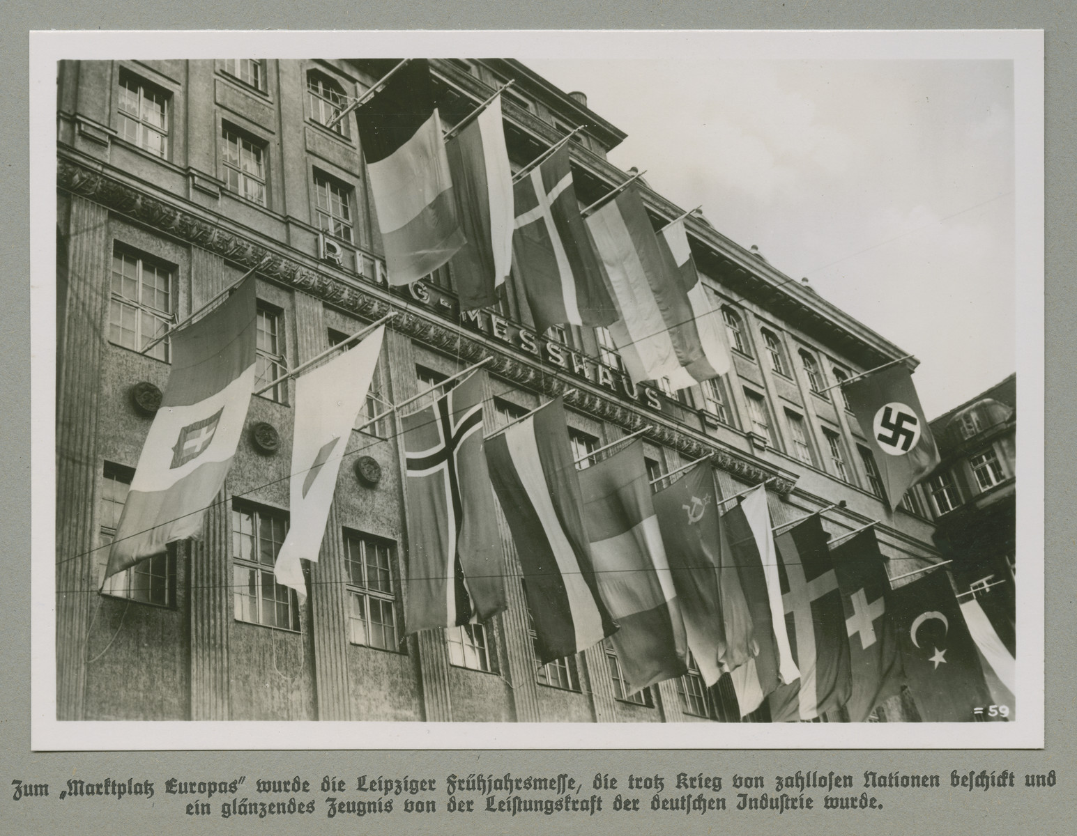 European flags are hung on the facade of the Ring-Messhaus in Leipzig, Germany.

The original caption reads: The Leipzig Spring Exhibition became "Europe's Marketplace," which in spite of the war has been fueled by countless Nations, and was a gleaming testimony to the power of German industry.