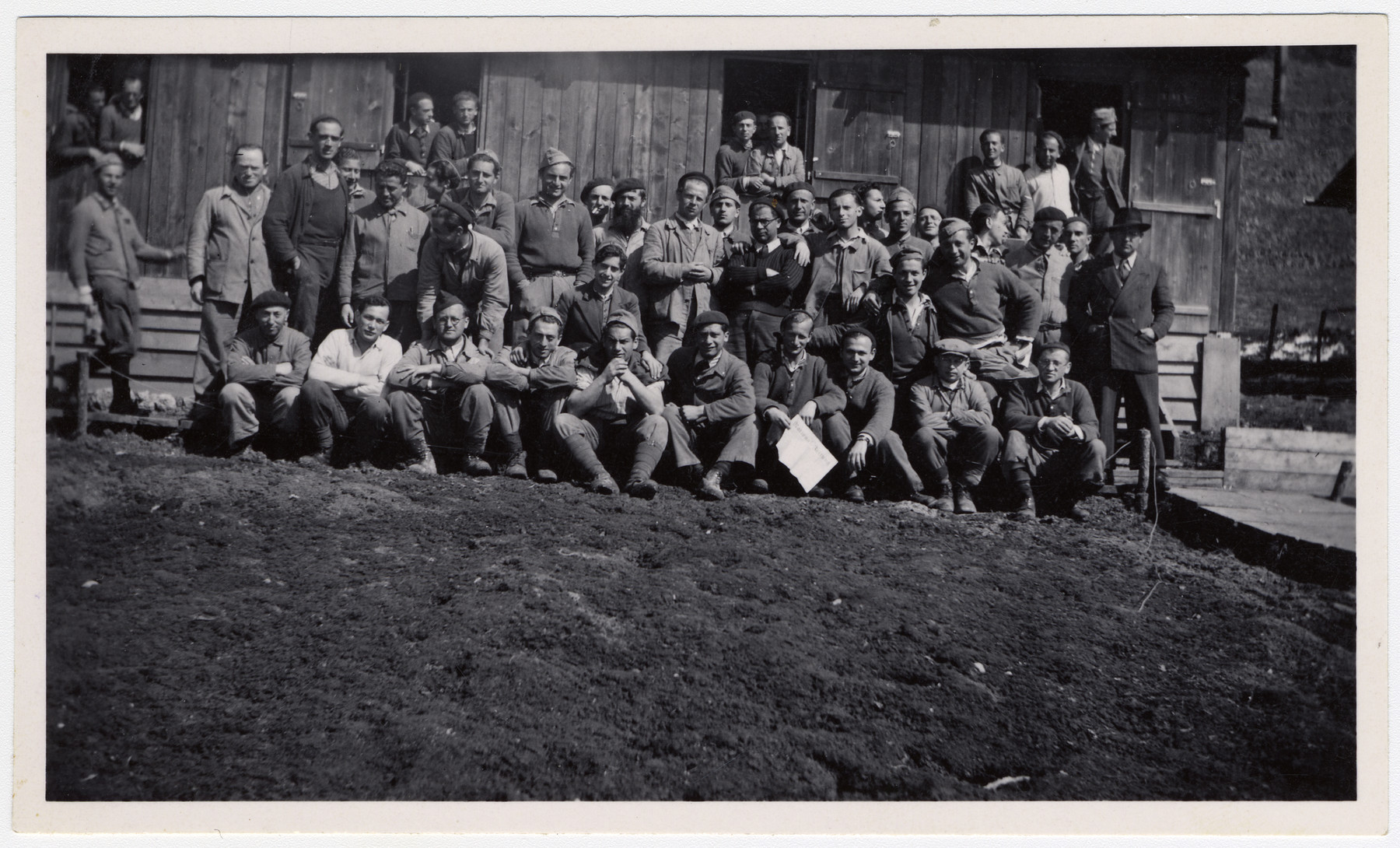 Group portrait of Jewish internees in an unidentified Swiss labor camp.

Max Schattner is standing in the middle with a black cap and light jacket, clasping his hands in front of his chest.