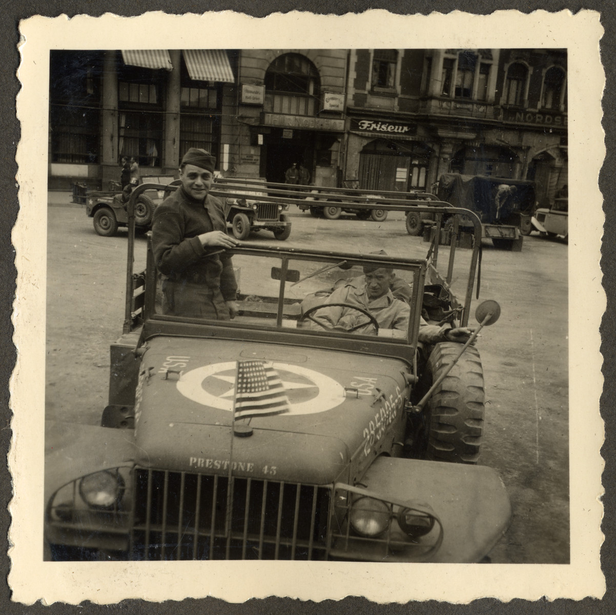 Joseph Eaton poses in his jeep while en route to Theresienstadt.  He arranged the trip in the hope of finding surviving relatives. 

Original caption reads: "On the way to Terezin."