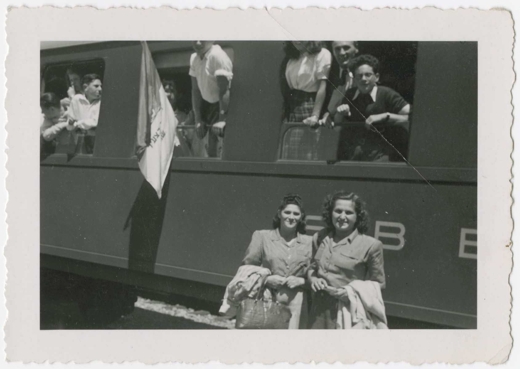 Hungarian Zionists who had come to Switzerland with the Kasztner transport pose inside and outside a train adorned with a Zionist flag.

Eva Weinberger is pictured in the front right, and Rosa Schiff is in the front left..