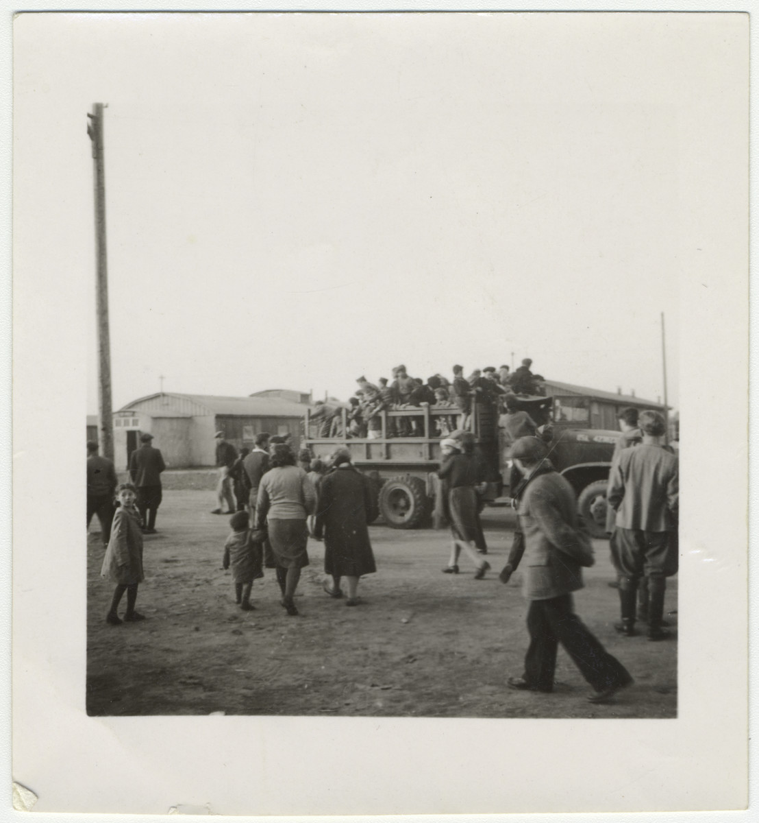 A group of children from a displaced persons crowds onto a truck.

David Marcus' original caption reads: "Barefooted children get a ride."