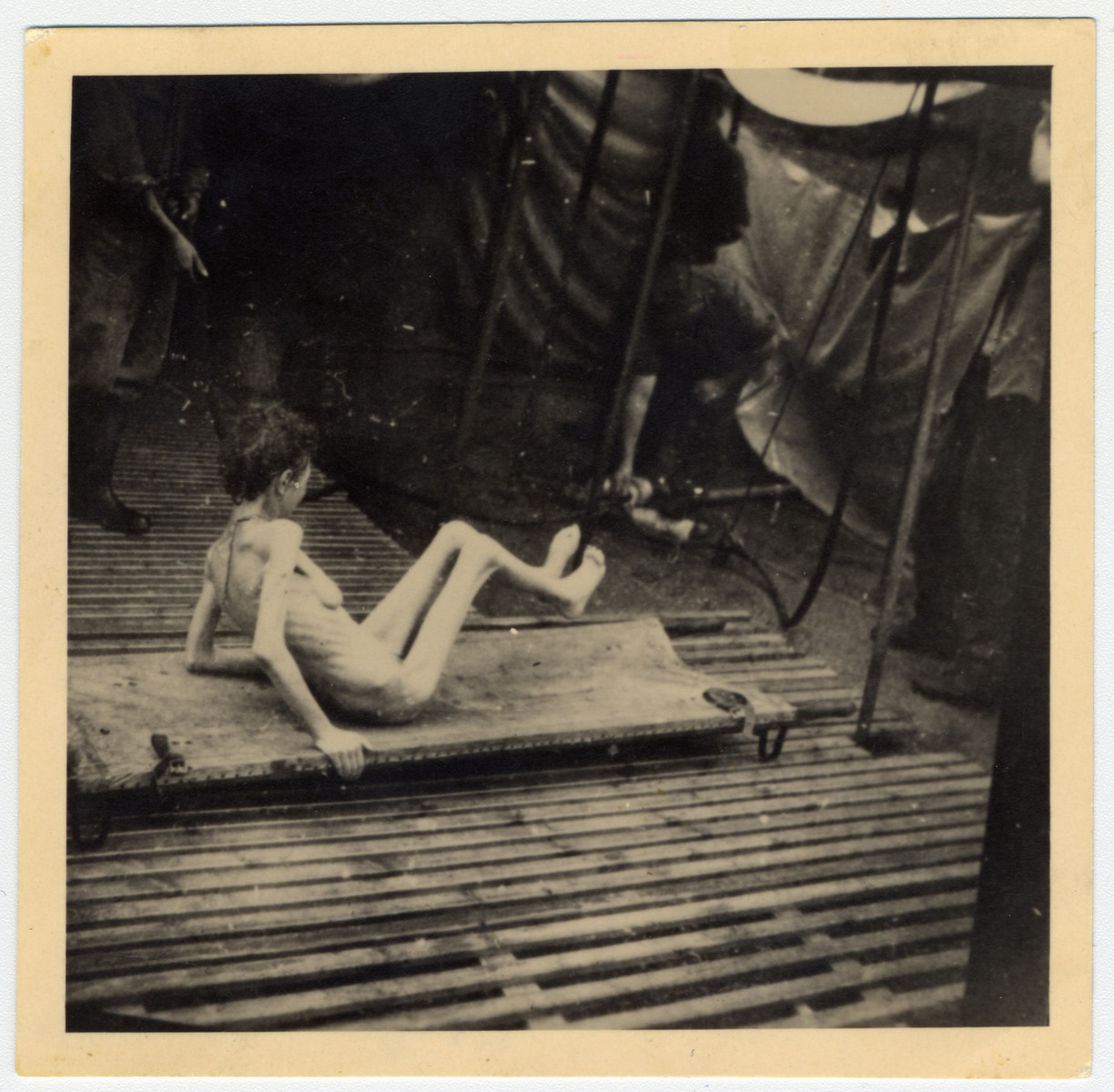 An emaciated survivor sits on a stretcher in Bergen-Belsen.