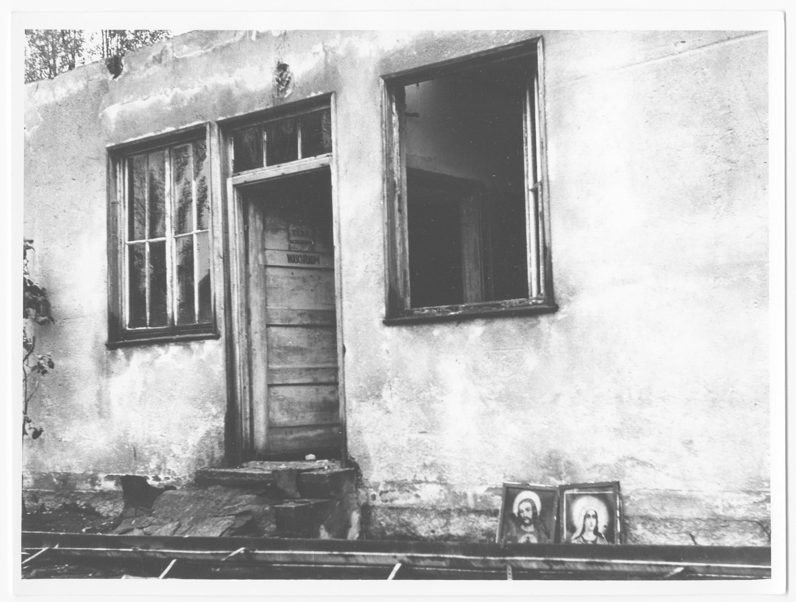 Postwar view of a barrack in Dachau with portraits of Jesus and Mary propped up against it.