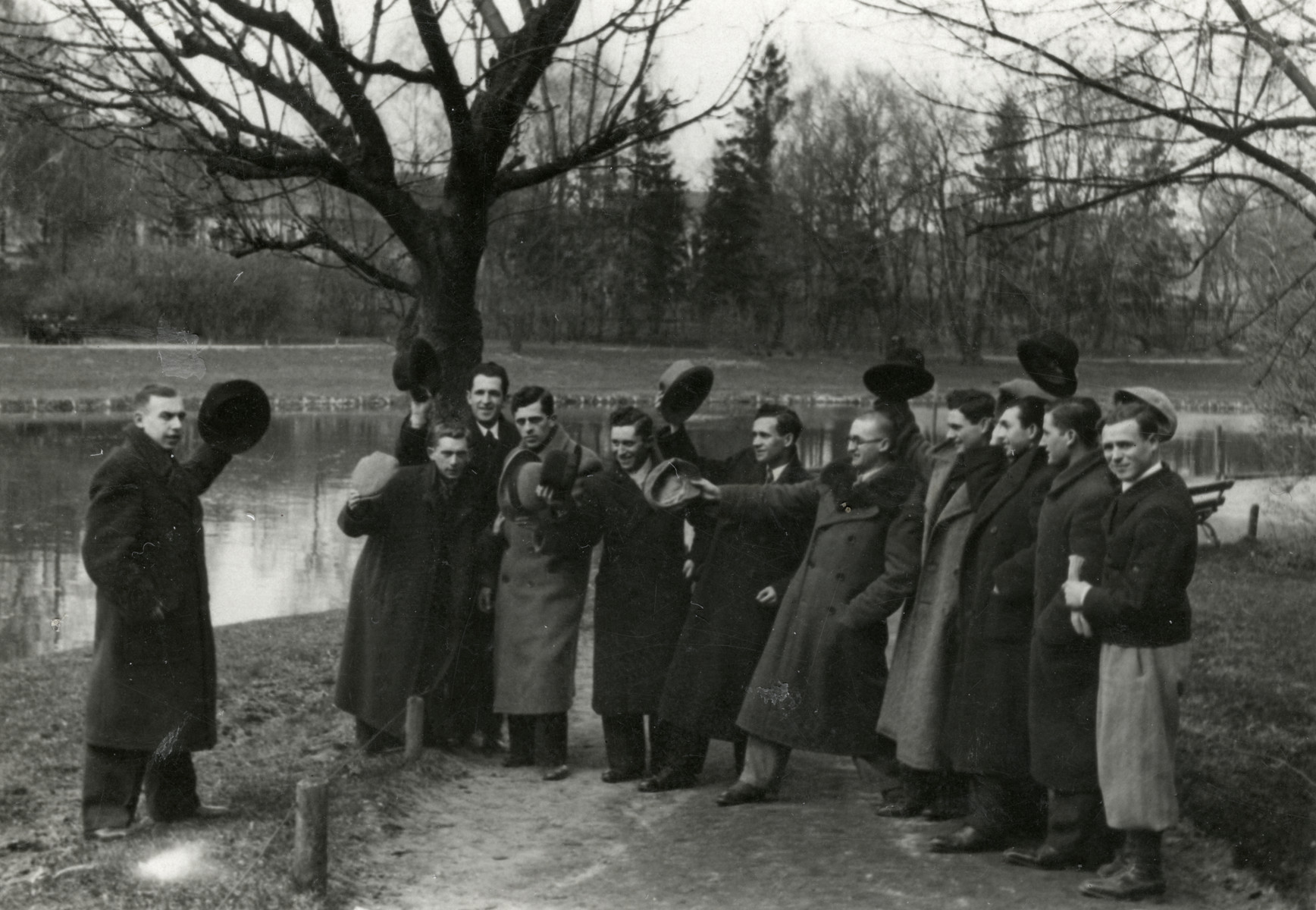 A group of friends waves their hats in a farewell to Isaac Rembichowski, who was leaving for Cuba. 

He later came to the United States.  Chaim Leichter is pictured second from the left.