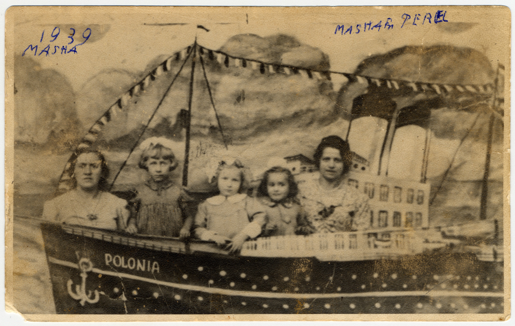 Studio portrait of women and children from Jewish family in Lodz posing against a mock boat,

The original Yiddish caption reads: