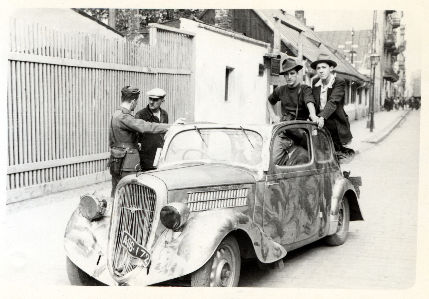 Polish civilians and a soldier loiter about an automobile [possibly Julien Bryan's car] in besieged Warsaw.