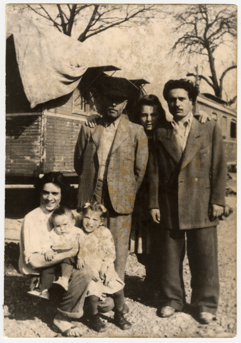 Group portrait of a Sinti family in front of their caravans. 

Pictured are members of the donor's family: in the middle is donor's grandfather, Johann Winterstein.  Next to him is his cousin and behind them is a German woman who was helping with the household.  Sitting is donor's uncle, Otto Winterstein, with his son Peter.  The little girl is the donor.