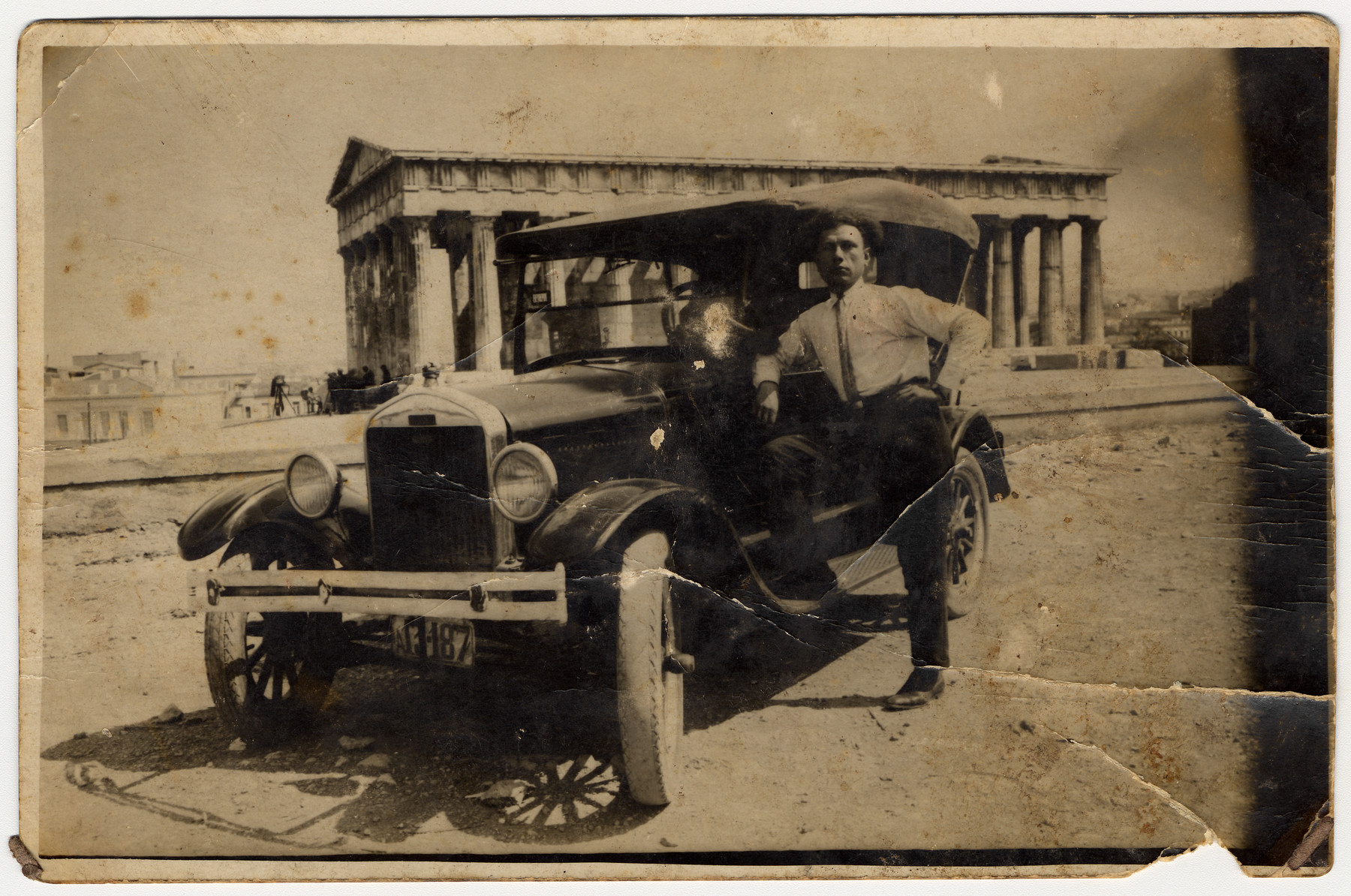 A Greek Jewish man stands next to his automobile parked in front of the Temple of Hephaestus (Thiseion).

Pictured is Elia Ackos, the uncle of the donor.