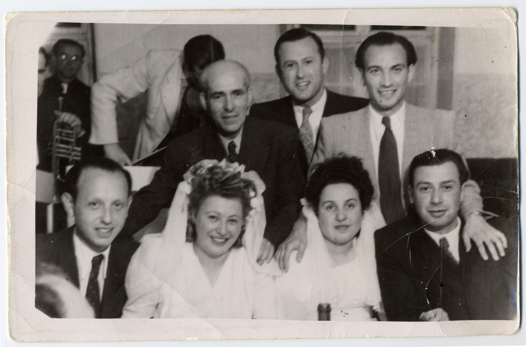 Two young couples celebrate their wedding in the Landsberg displaced persons camp. 

Pictured on the left are Benjamin Jumek Milich and Halina Gozdzik Milich and on the right are Anka Milich Szwarcberg and  Bolek Szwarcberg.  Behind them, on the left, stands Benjamin's stepfather Mozyglod.