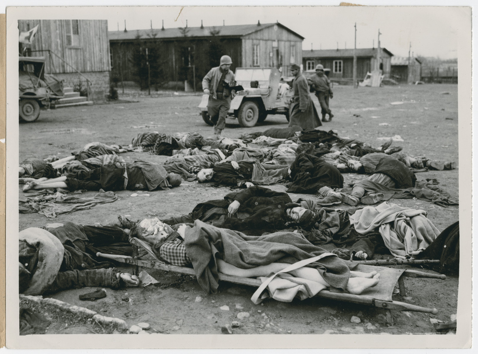 The U.S. Army inspects bodies of slain prisoners at the Ohrdruf concentration camp.

Original caption reads:  "Here are the bodies of some of the slain prisoners.  The case of the man on the litter in the foreground is being carefully investigated.  According to survivors, this man always said he was an American, and he is believed to have been either a flyer or a paratrooper".