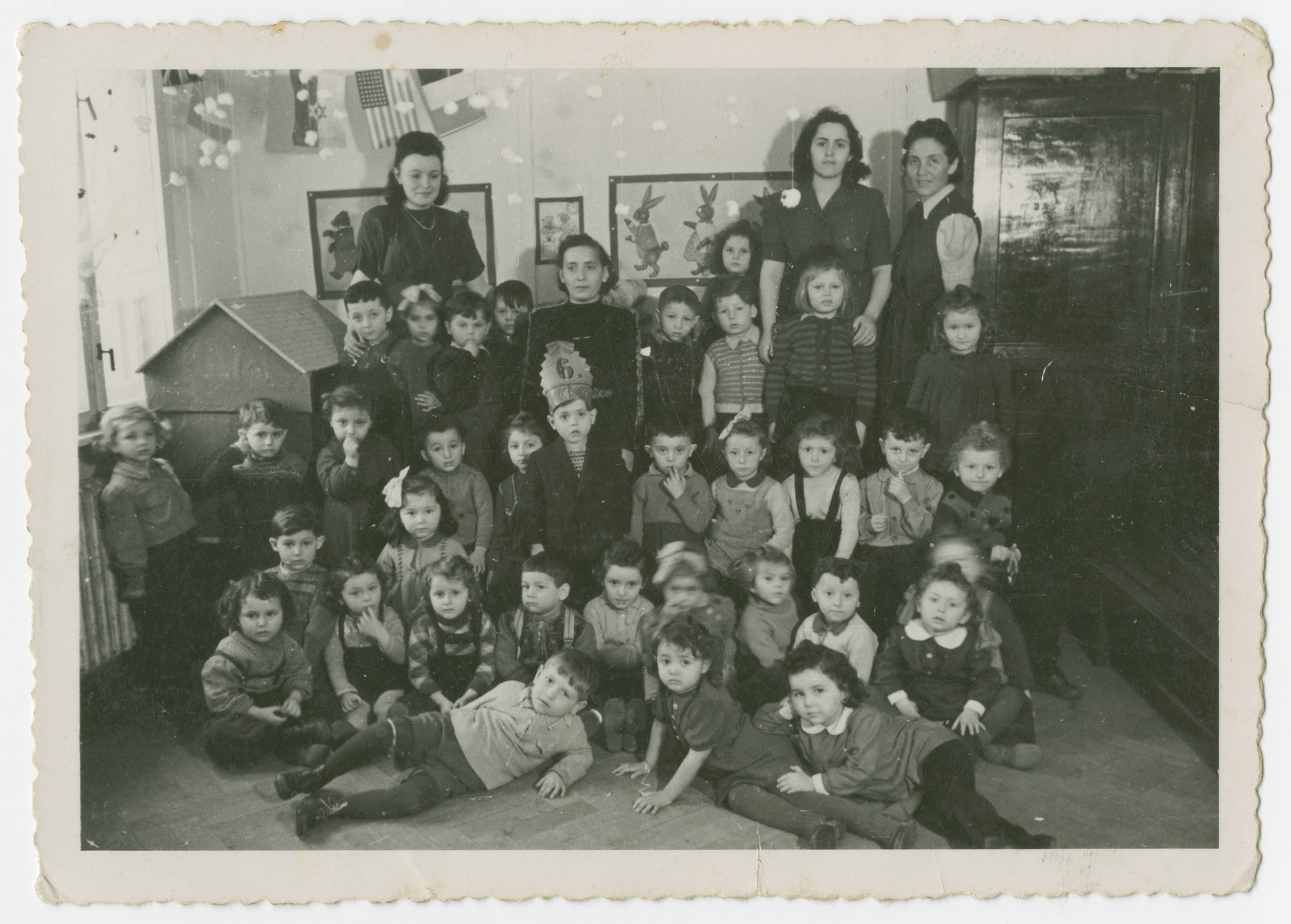 Group portrait of young children in a school in the Schlachtensee displaced persons camp. 

Joseph Fridling, wearing a special hat marking his sixth birthday, stands in the center.