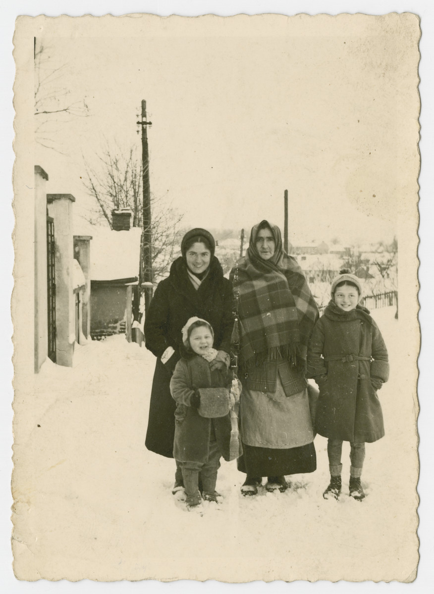 Three generations of women stand in the snow in the Bochnia ghetto.

From left to right are Rywa Roth, her daughter Anna, her mother Brendel Kleinberg and her daughter Mina.