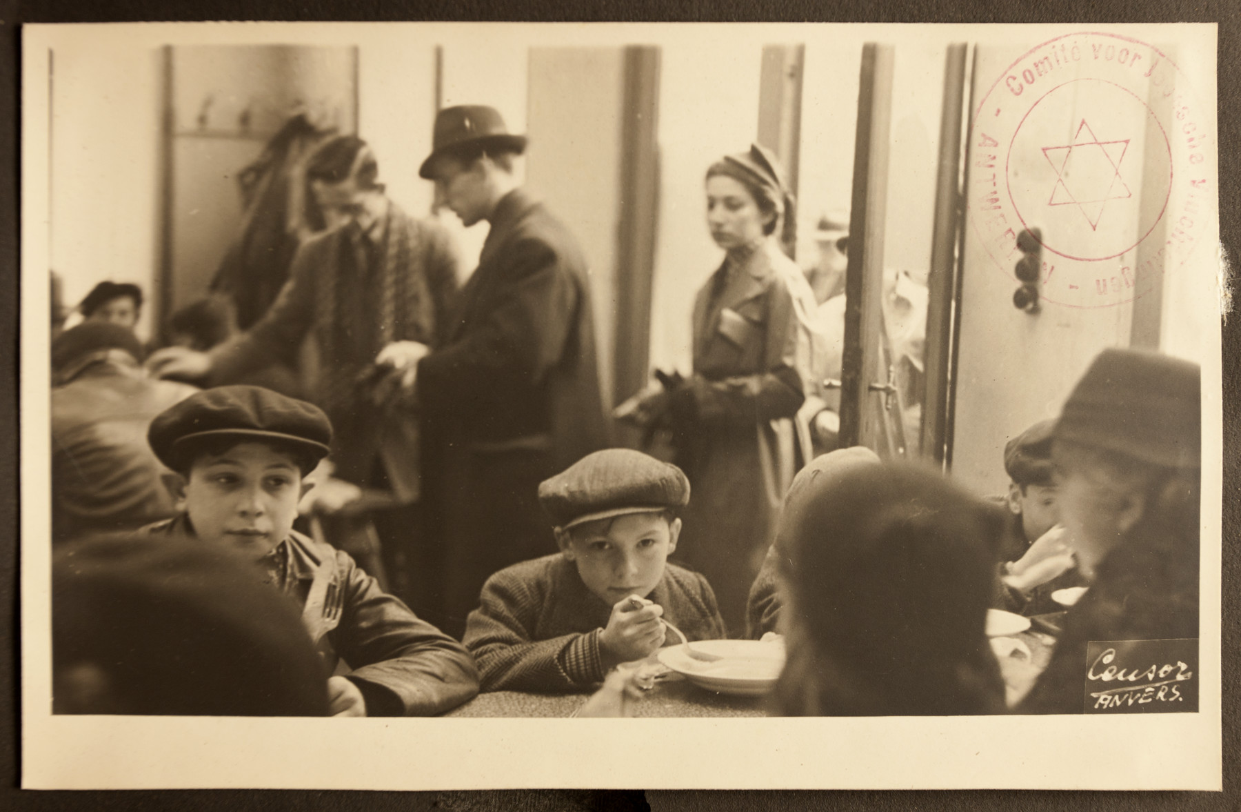 Women and children eat in the dining room of the Jewish Refugee Aid Committee of Antwerp.