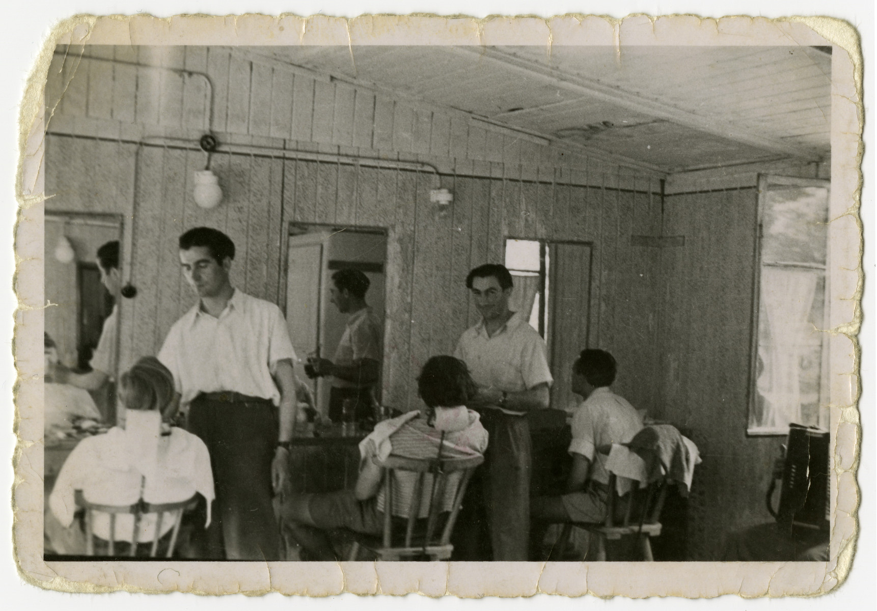 David Burdowski works as a barber [probably in the Feldafing displaced persons camp].

The barber pictured on the left is Chaim (Leo) Goldberg.